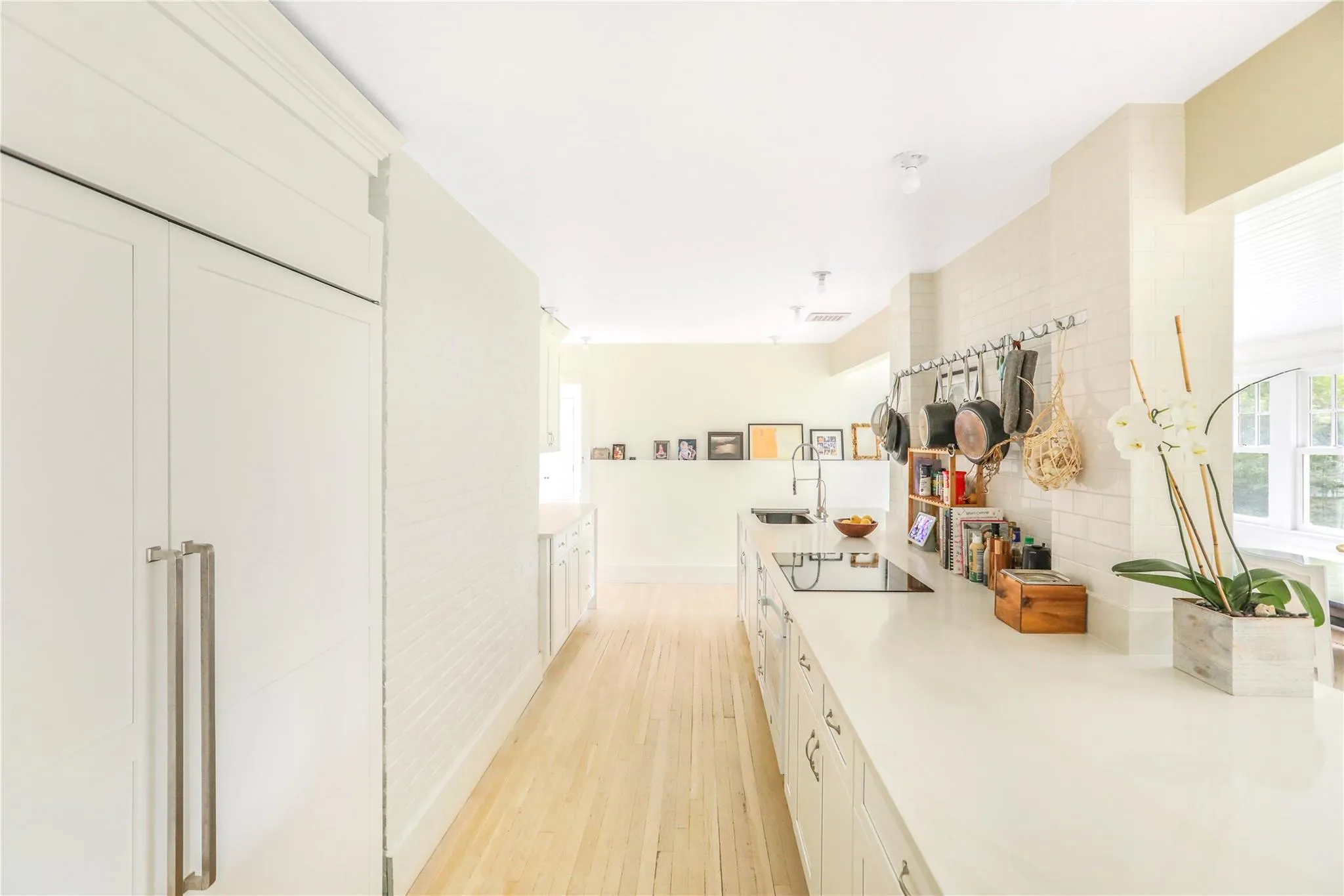 Kitchen with a sink, light wood-style floors, white cabinetry, light countertops, and black electric stovetop Kitchen with a sink, light wood-style floors, white cabinetry, light countertops, and black electric stovetop