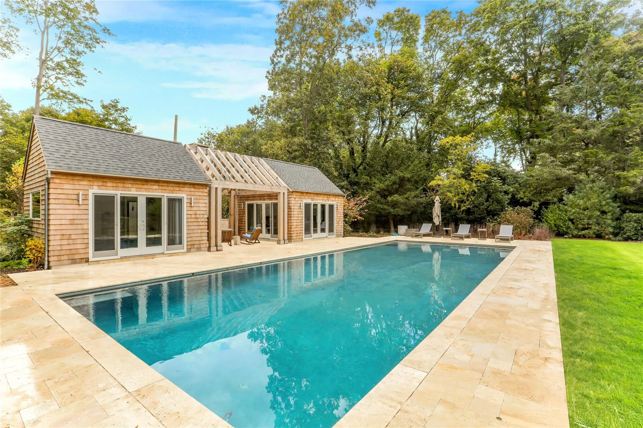 Swimming pool with french doors, a storage structure, a patio, a lawn, and an outbuilding Swimming pool with french doors, a storage structure, a patio, a lawn, and an outbuilding