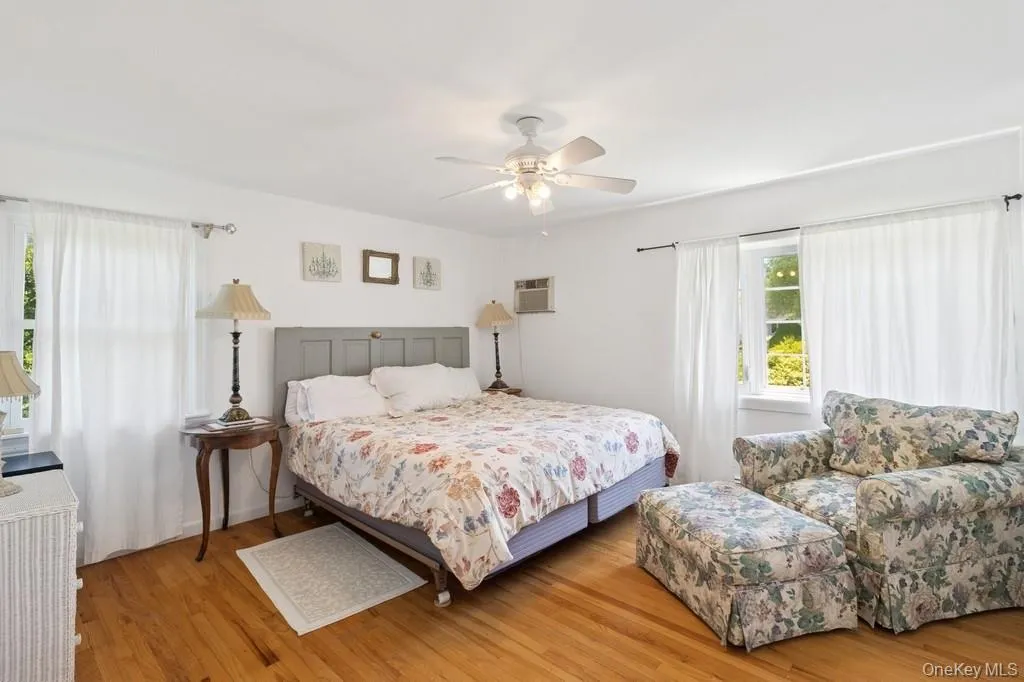 Bedroom featuring light wood-type flooring, a wall unit AC, and ceiling fan Bedroom featuring light wood-type flooring, a wall unit AC, and ceiling fan