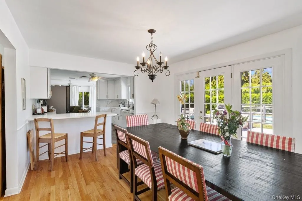 Dining space featuring healthy amount of natural light, ceiling fan, light wood finished floors, and a chandelier Dining space featuring healthy amount of natural light, ceiling fan, light wood finished floors, and a chandelier
