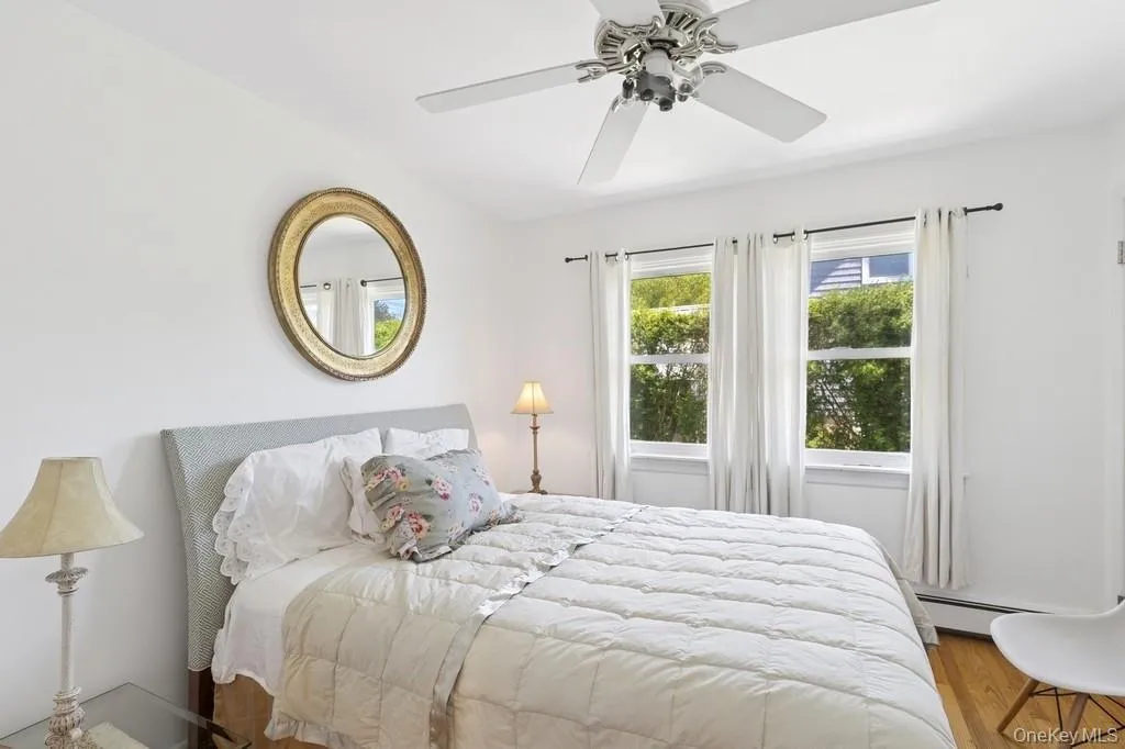 Bedroom featuring wood finished floors, baseboard heating, and a ceiling fan Bedroom featuring wood finished floors, baseboard heating, and a ceiling fan