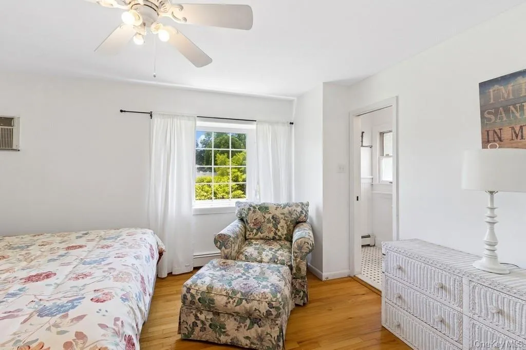 Bedroom with light wood-style flooring, ceiling fan, and a baseboard heating unit Bedroom with light wood-style flooring, ceiling fan, and a baseboard heating unit