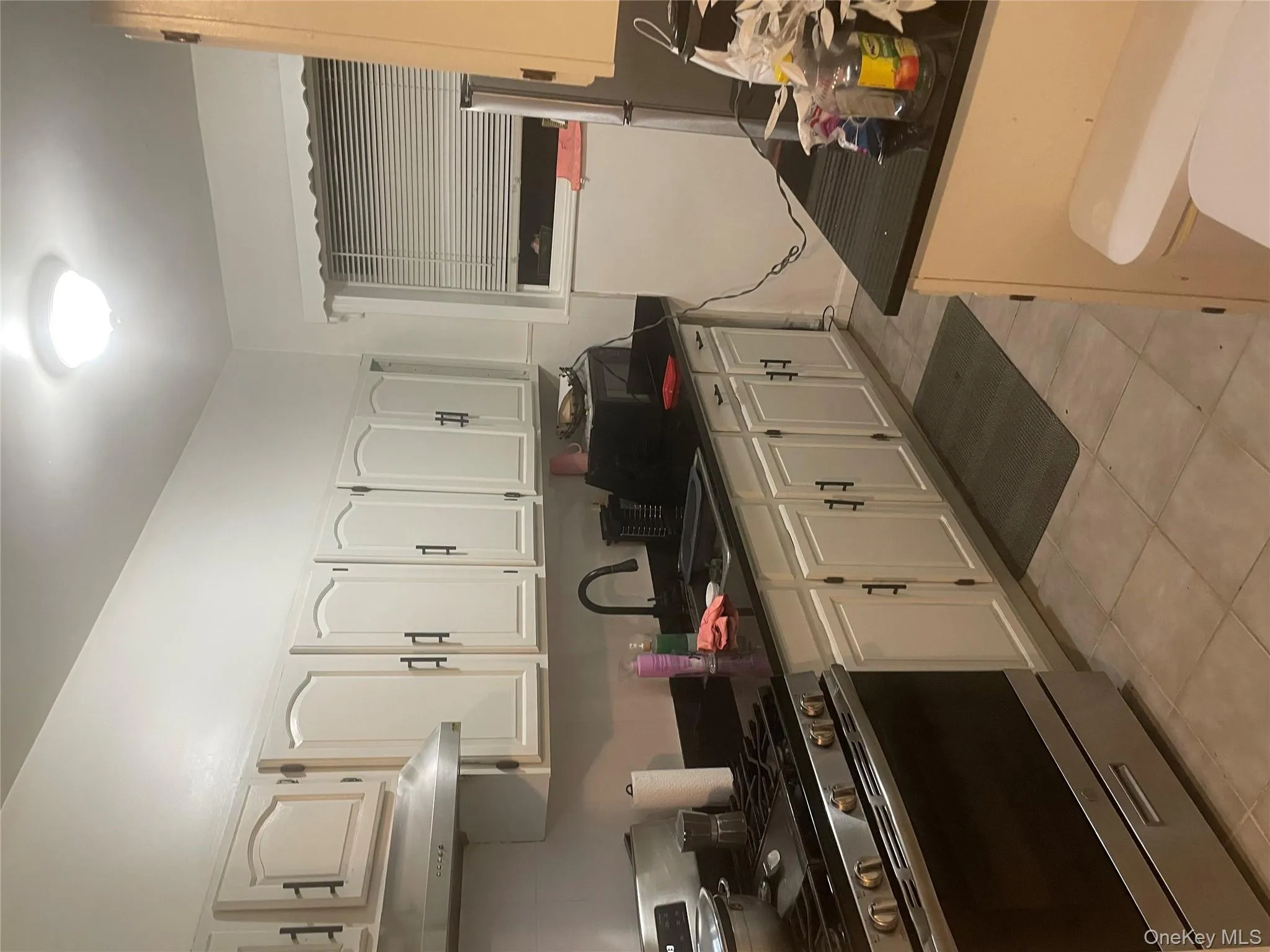 Kitchen featuring exhaust hood, stove, a sink, white cabinetry, and dark countertops Kitchen featuring exhaust hood, stove, a sink, white cabinetry, and dark countertops