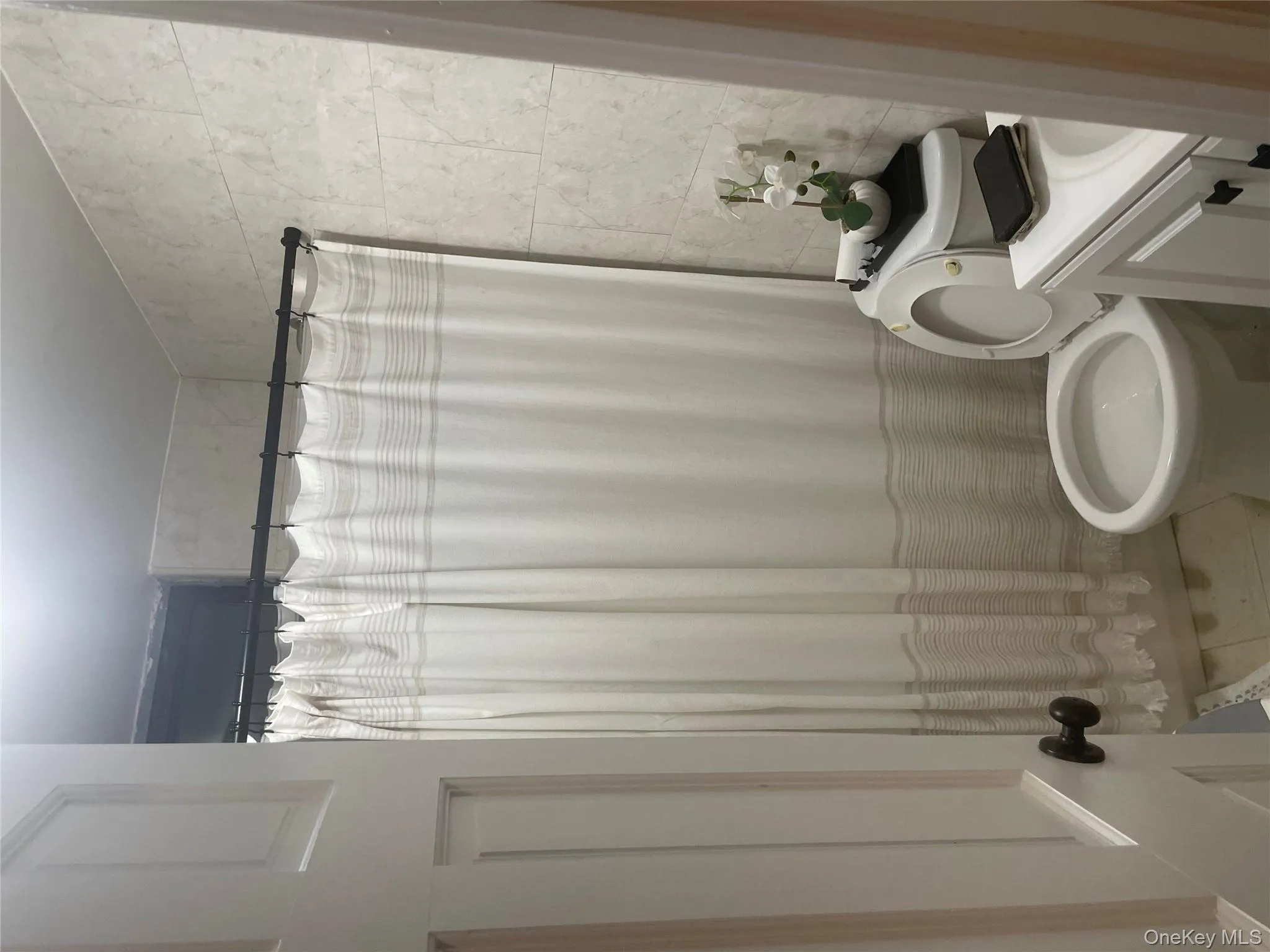 Full bath with tile walls, toilet, vanity, tile patterned floors, and a shower with curtain Full bath with tile walls, toilet, vanity, tile patterned floors, and a shower with curtain