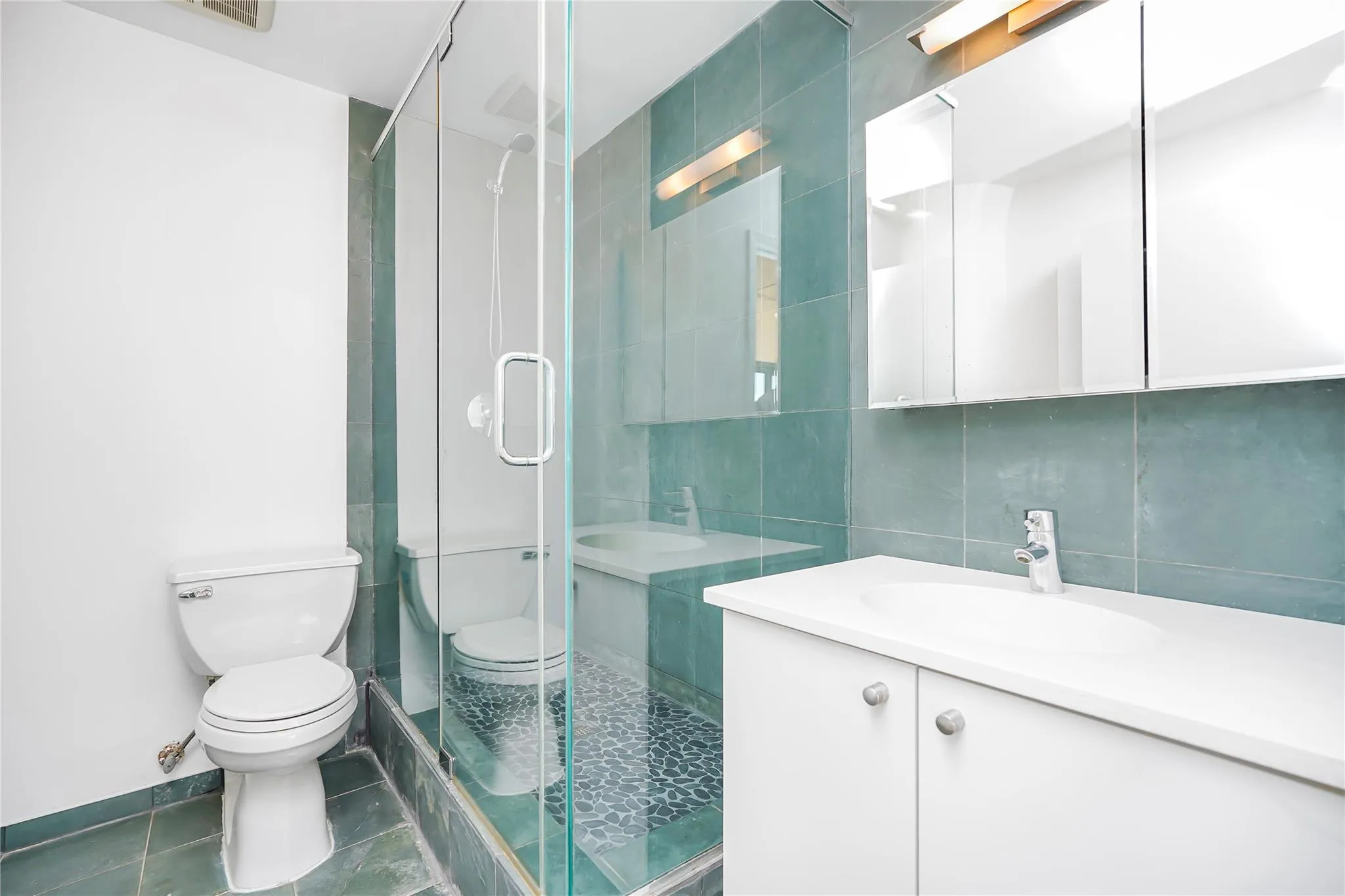 Bathroom featuring toilet, a shower stall, vanity, tile patterned floors, and backsplash Bathroom featuring toilet, a shower stall, vanity, tile patterned floors, and backsplash