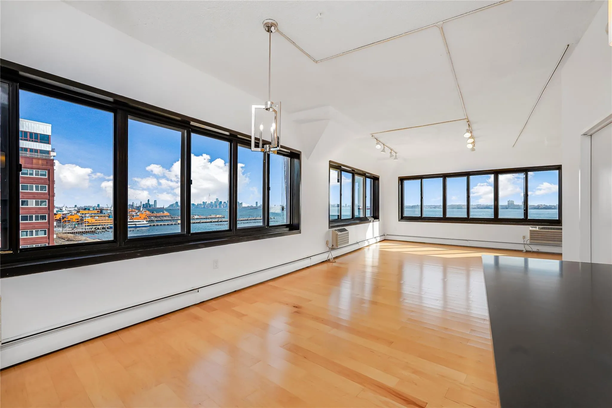 Spare room featuring a baseboard radiator, rail lighting, wood finished floors, and a chandelier Spare room featuring a baseboard radiator, rail lighting, wood finished floors, and a chandelier