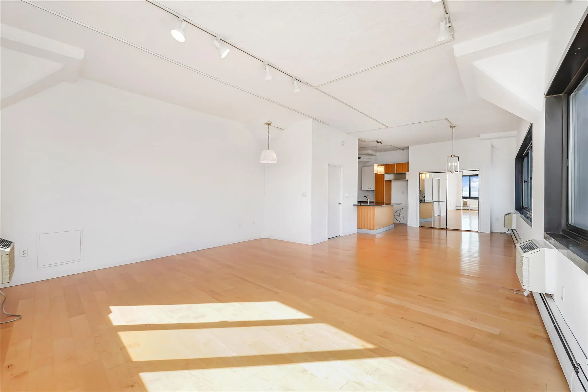 Unfurnished living room with rail lighting, a baseboard radiator, light wood-style flooring, and a sink Unfurnished living room with rail lighting, a baseboard radiator, light wood-style flooring, and a sink