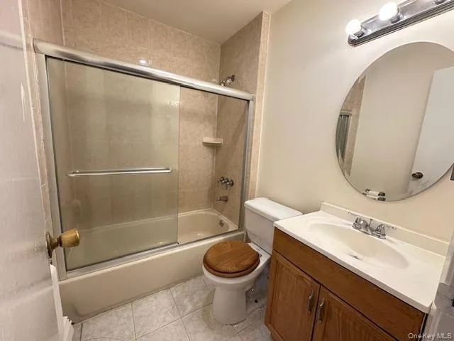 Bathroom with vanity, enclosed tub / shower combo, and light tile patterned floors Bathroom with vanity, enclosed tub / shower combo, and light tile patterned floors