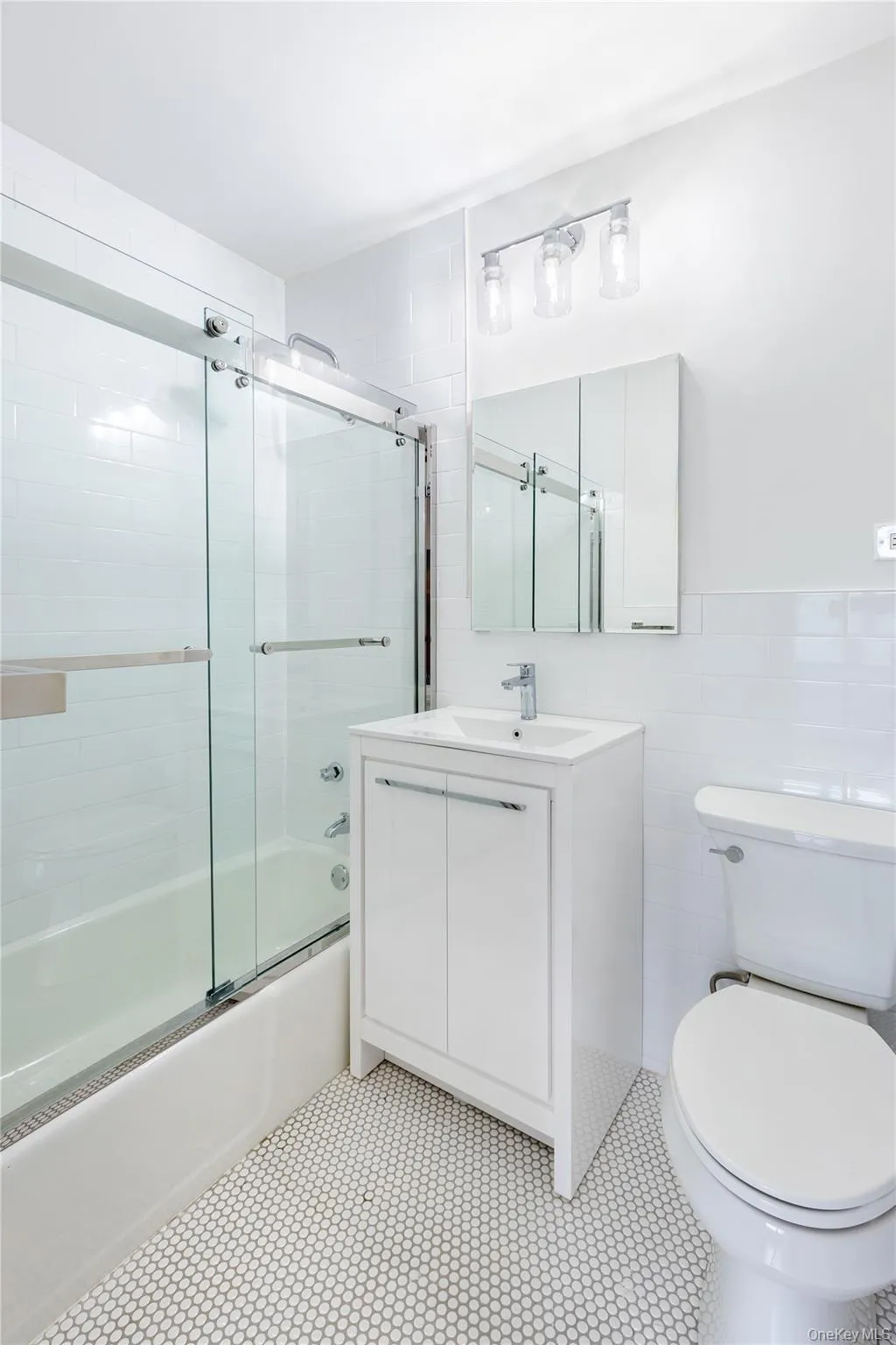 Full bath with toilet, bath / shower combo with glass door, vanity, tile walls, and tile patterned flooring Full bath with toilet, bath / shower combo with glass door, vanity, tile walls, and tile patterned flooring