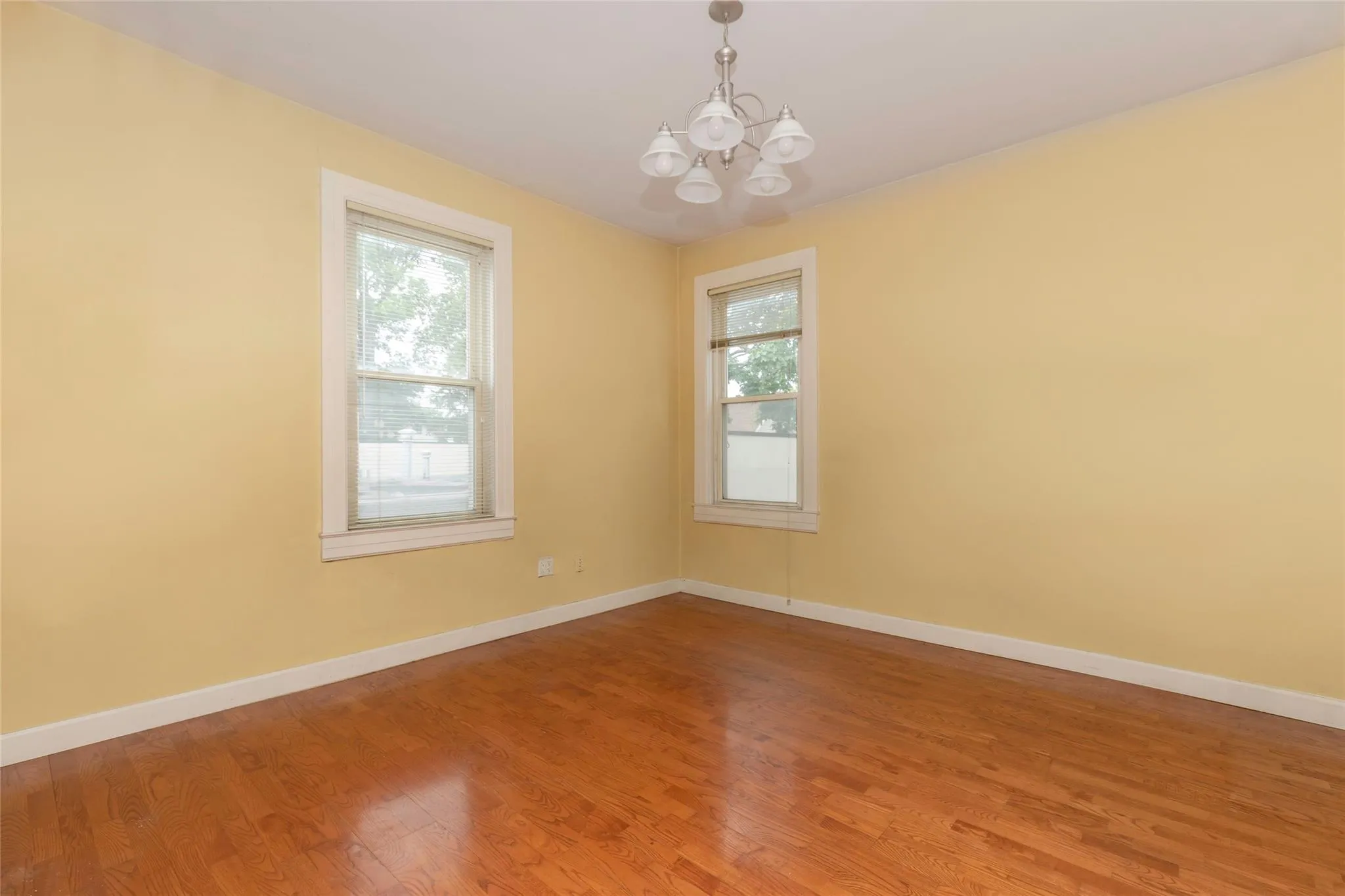 Spare room featuring plenty of natural light, a chandelier, light wood-style floors, and baseboards Spare room featuring plenty of natural light, a chandelier, light wood-style floors, and baseboards