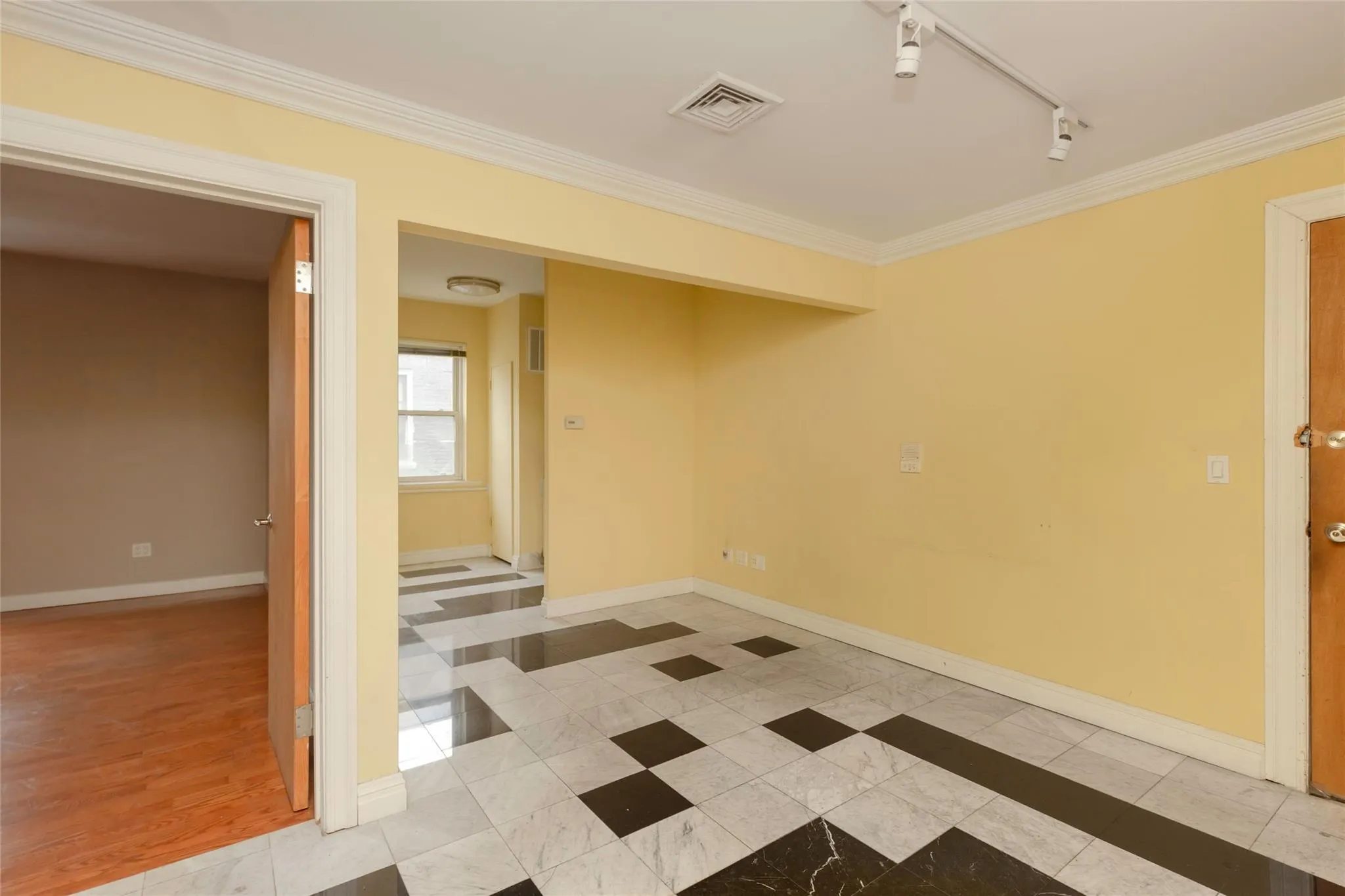 Tiled empty room with crown molding, baseboards, and track lighting Tiled empty room with crown molding, baseboards, and track lighting