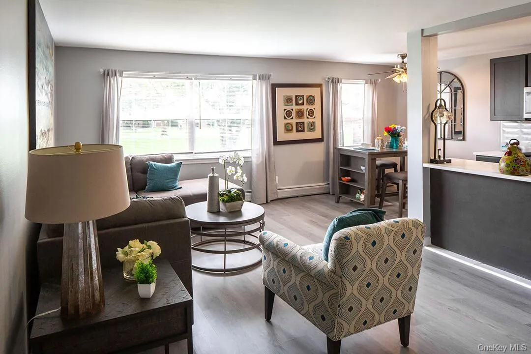 Living area with plenty of natural light, light wood finished floors, ceiling fan, and a baseboard heating unit Living area with plenty of natural light, light wood finished floors, ceiling fan, and a baseboard heating unit