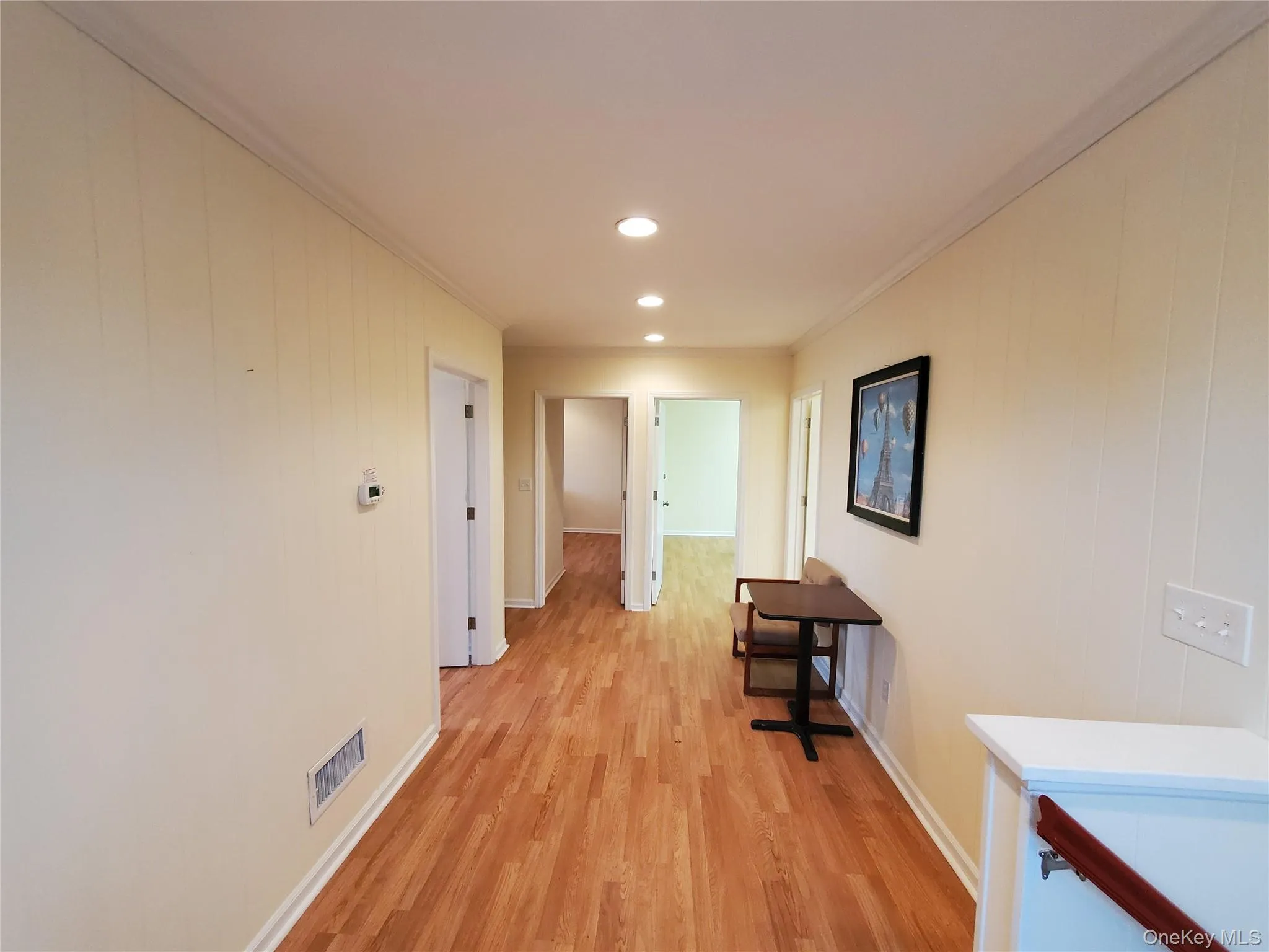 Hall with light wood-type flooring, crown molding, baseboards, and recessed lighting Hall with light wood-type flooring, crown molding, baseboards, and recessed lighting