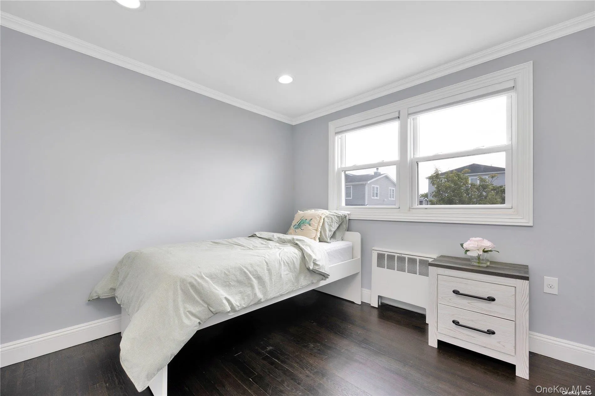 Bedroom with radiator heating unit, baseboards, recessed lighting, crown molding, and dark wood-style flooring Bedroom with radiator heating unit, baseboards, recessed lighting, crown molding, and dark wood-style flooring