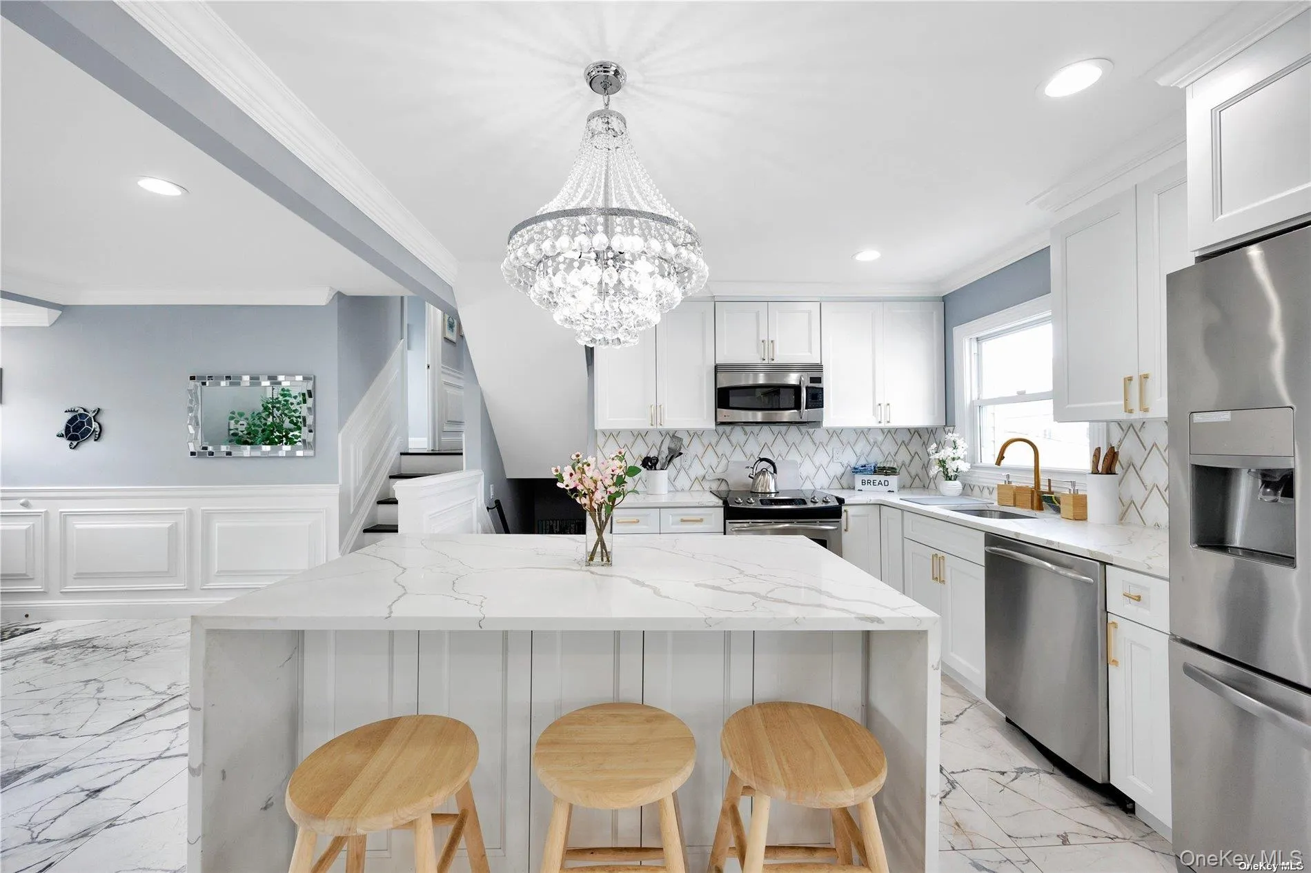 Kitchen featuring appliances with stainless steel finishes, a sink, light marble finish flooring, a breakfast bar, and recessed lighting Kitchen featuring appliances with stainless steel finishes, a sink, light marble finish flooring, a breakfast bar, and recessed lighting
