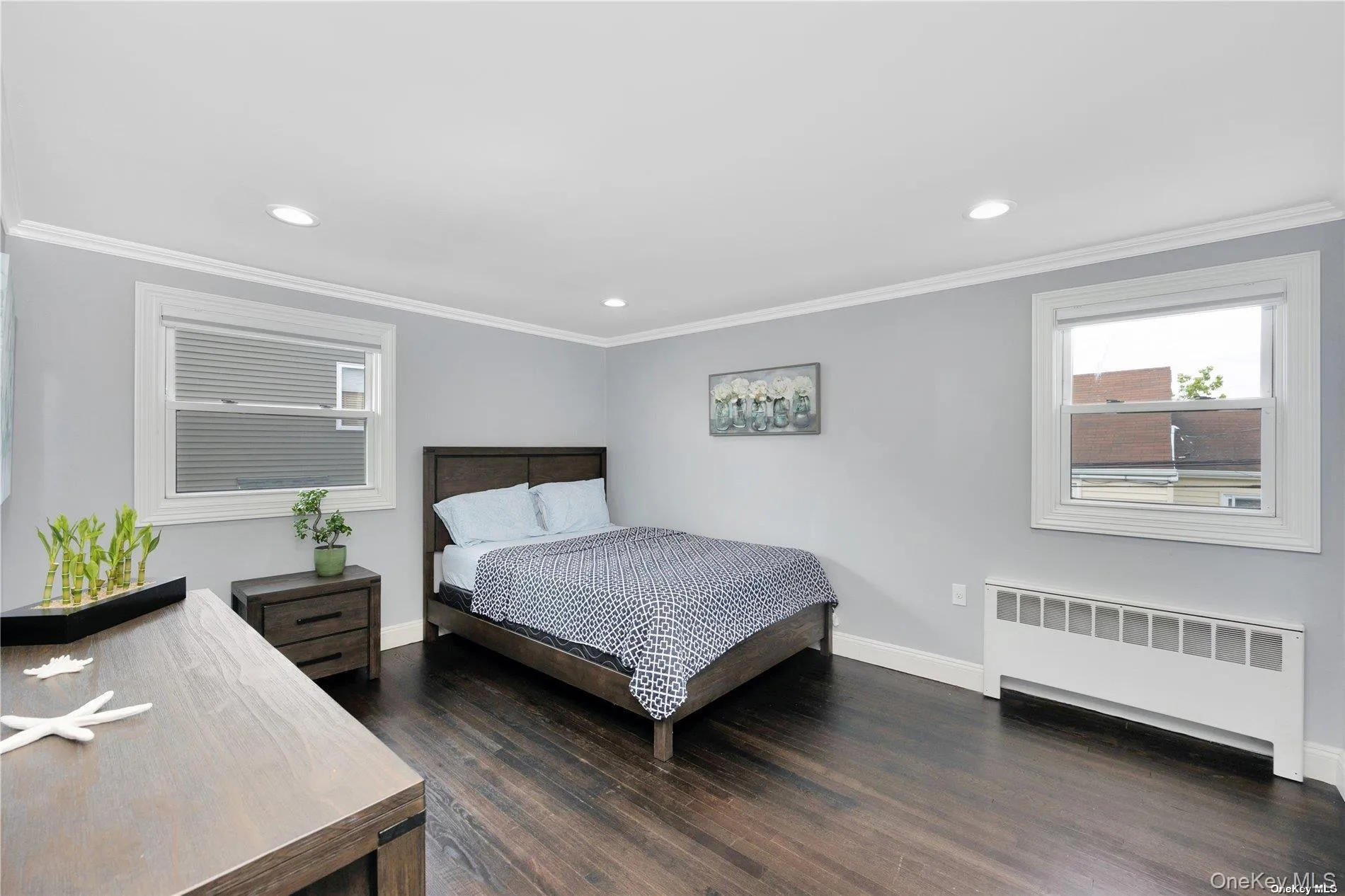 Bedroom featuring radiator, baseboards, dark wood-style floors, recessed lighting, and crown molding Bedroom featuring radiator, baseboards, dark wood-style floors, recessed lighting, and crown molding