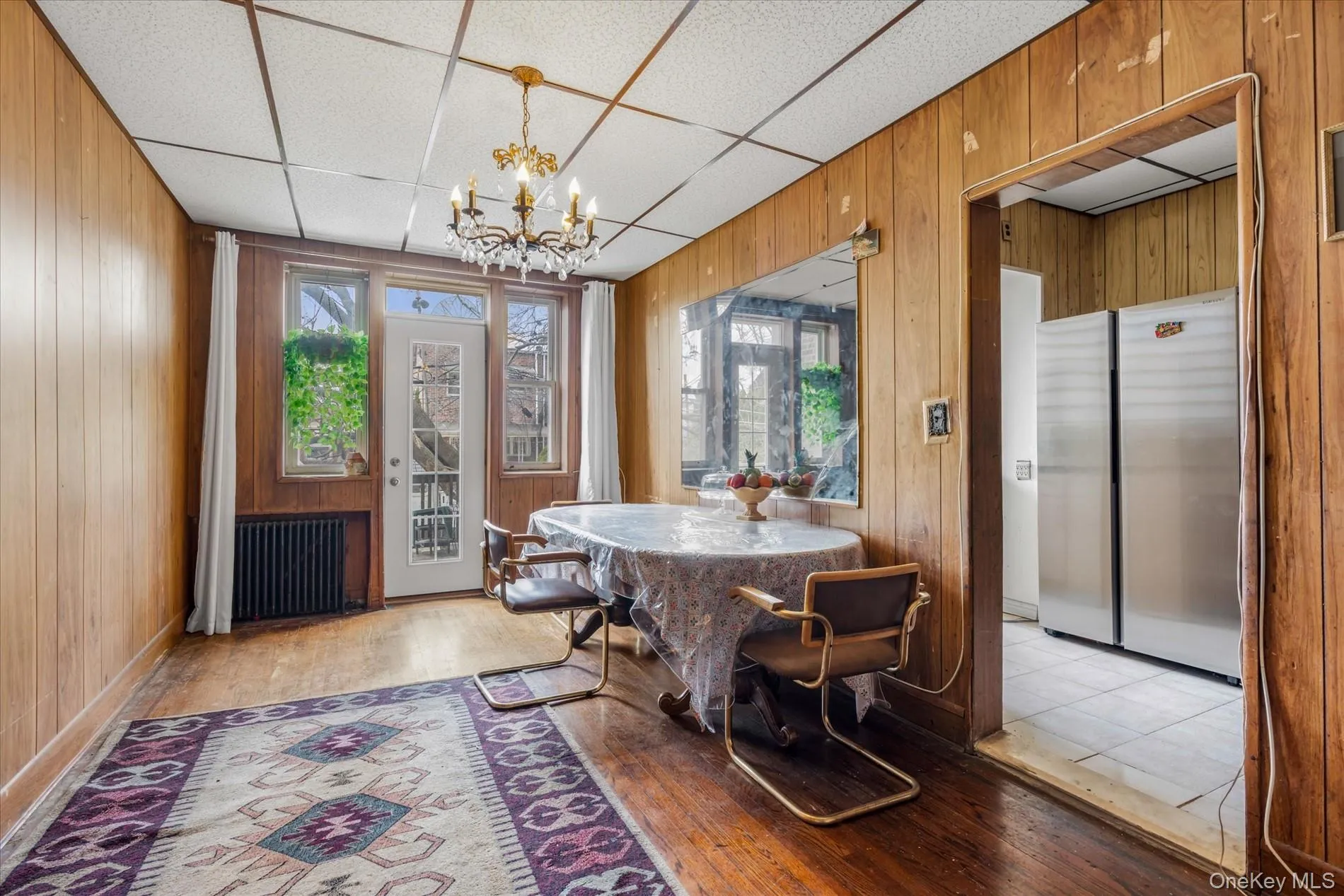 Dining area with radiator heating unit, a chandelier, wood walls, healthy amount of natural light, and light wood-style floors Dining area with radiator heating unit, a chandelier, wood walls, healthy amount of natural light, and light wood-style floors