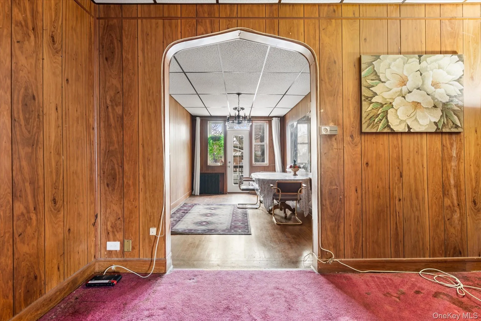 Carpeted entrance foyer with baseboards, wooden walls, and a paneled ceiling Carpeted entrance foyer with baseboards, wooden walls, and a paneled ceiling
