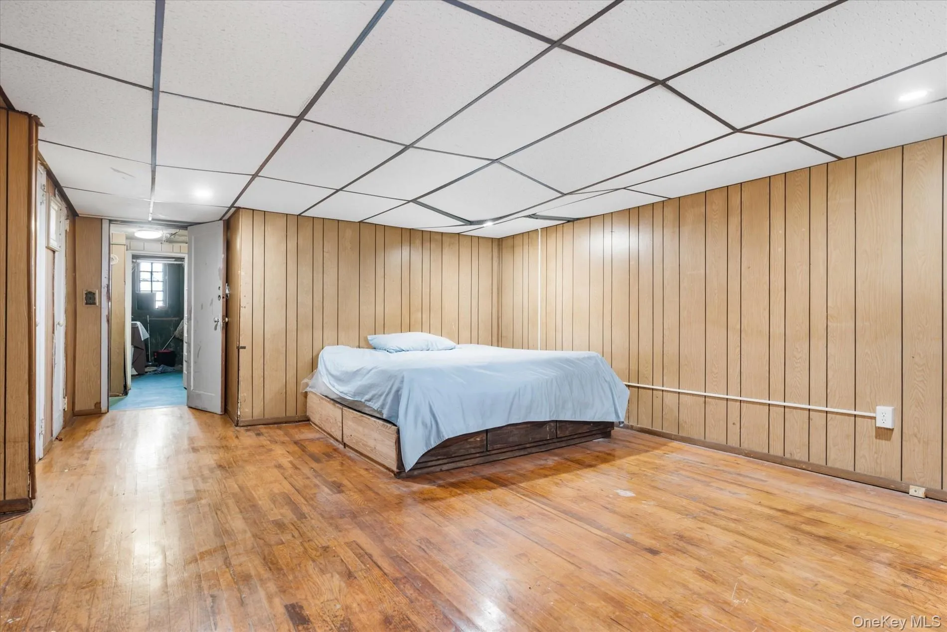 Bedroom featuring a paneled ceiling, hardwood / wood-style flooring, and wooden walls Bedroom featuring a paneled ceiling, hardwood / wood-style flooring, and wooden walls