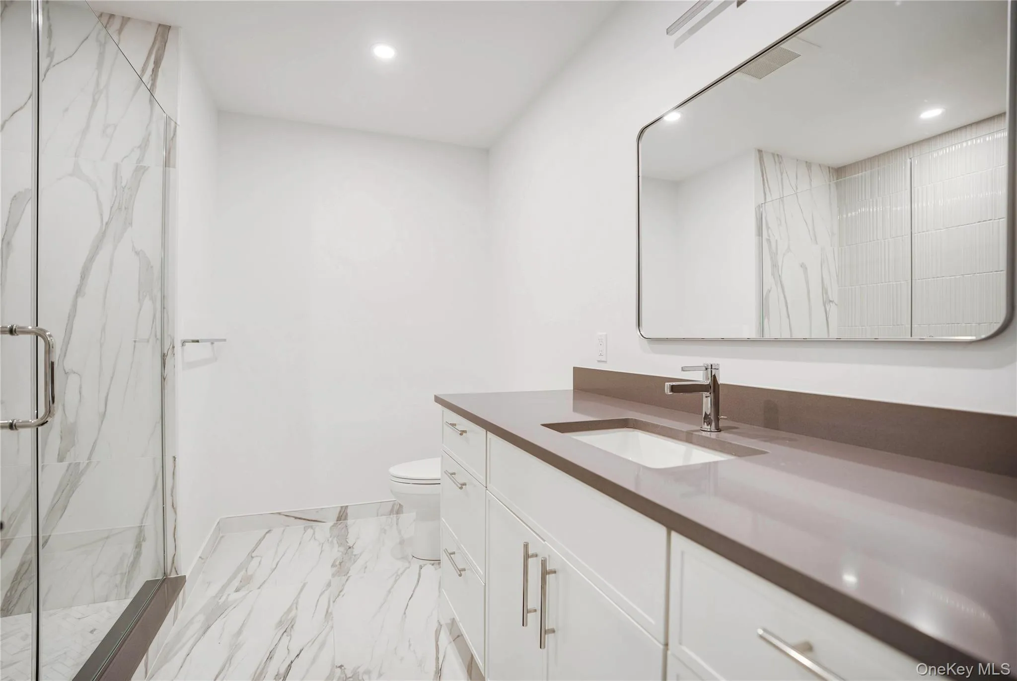 Full bath with a marble finish shower, toilet, marble look tiles, recessed lighting, and vanity Full bath with a marble finish shower, toilet, marble look tiles, recessed lighting, and vanity