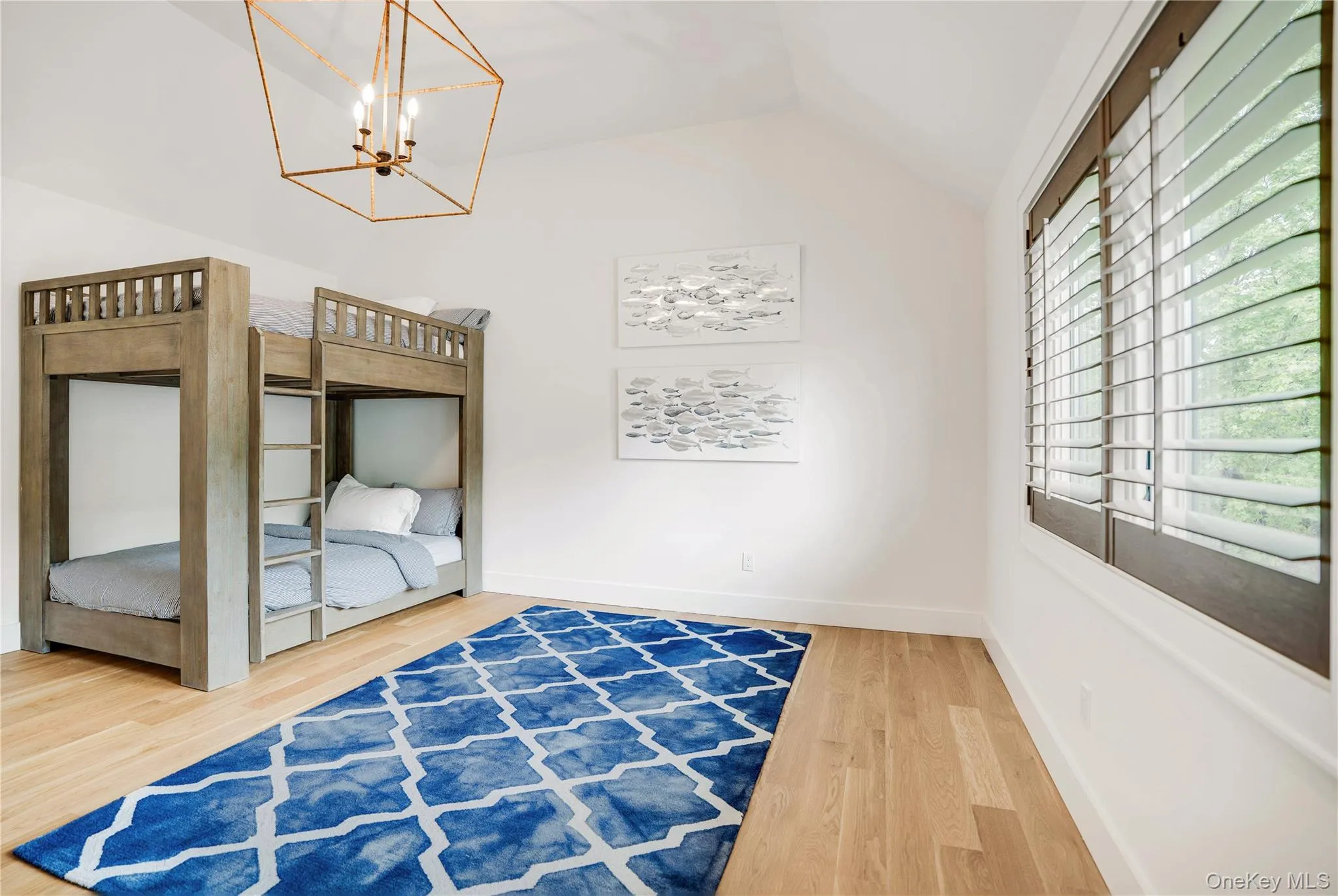 Unfurnished bedroom with lofted ceiling, wood finished floors, a chandelier, and baseboards Unfurnished bedroom with lofted ceiling, wood finished floors, a chandelier, and baseboards