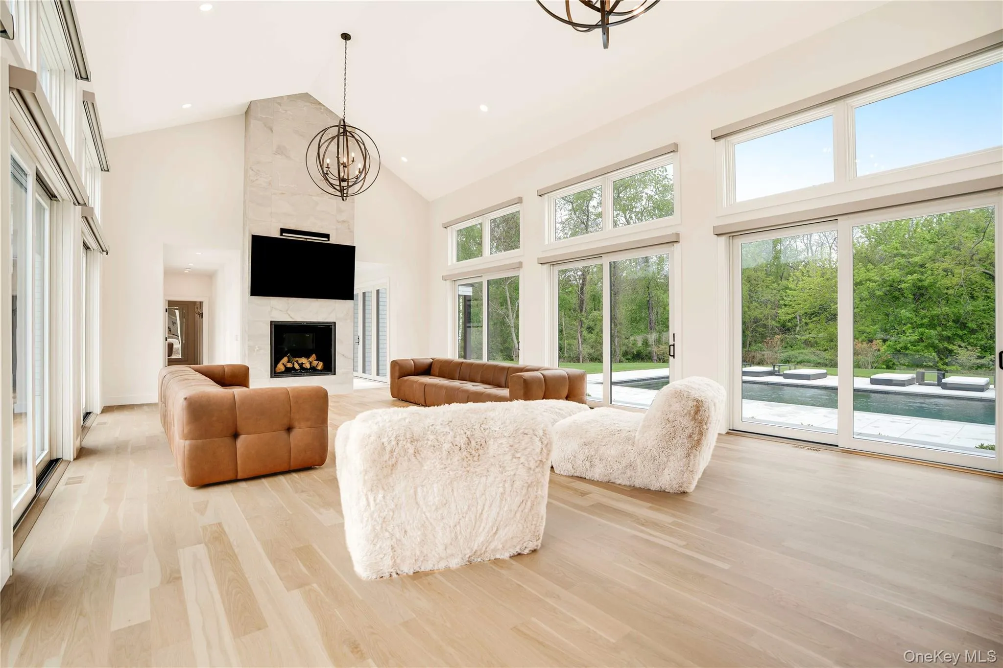Living area with high vaulted ceiling, a chandelier, light wood-style flooring, a high end fireplace, and recessed lighting Living area with high vaulted ceiling, a chandelier, light wood-style flooring, a high end fireplace, and recessed lighting