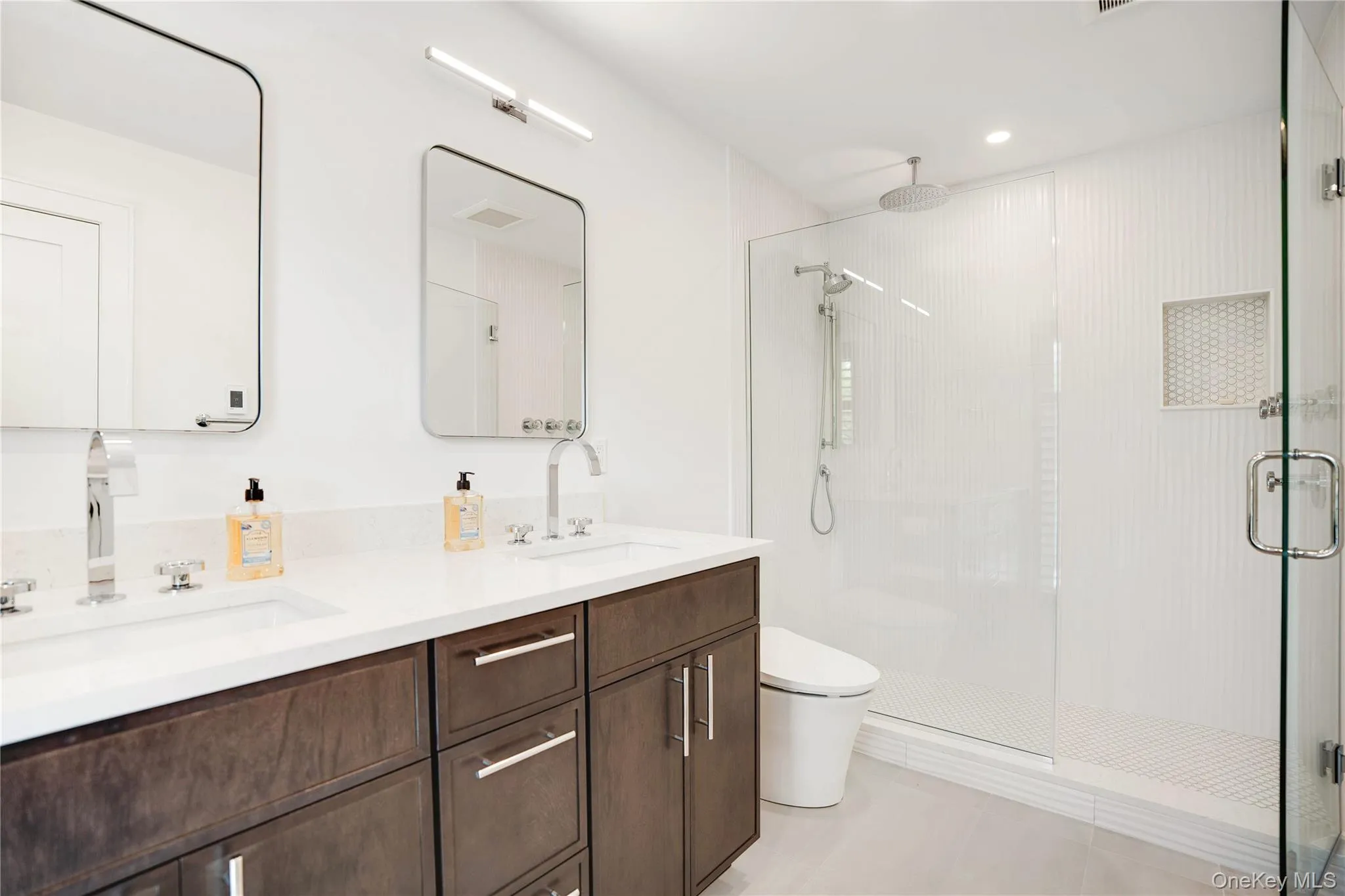 Bathroom featuring a shower stall, double vanity, and toilet Bathroom featuring a shower stall, double vanity, and toilet