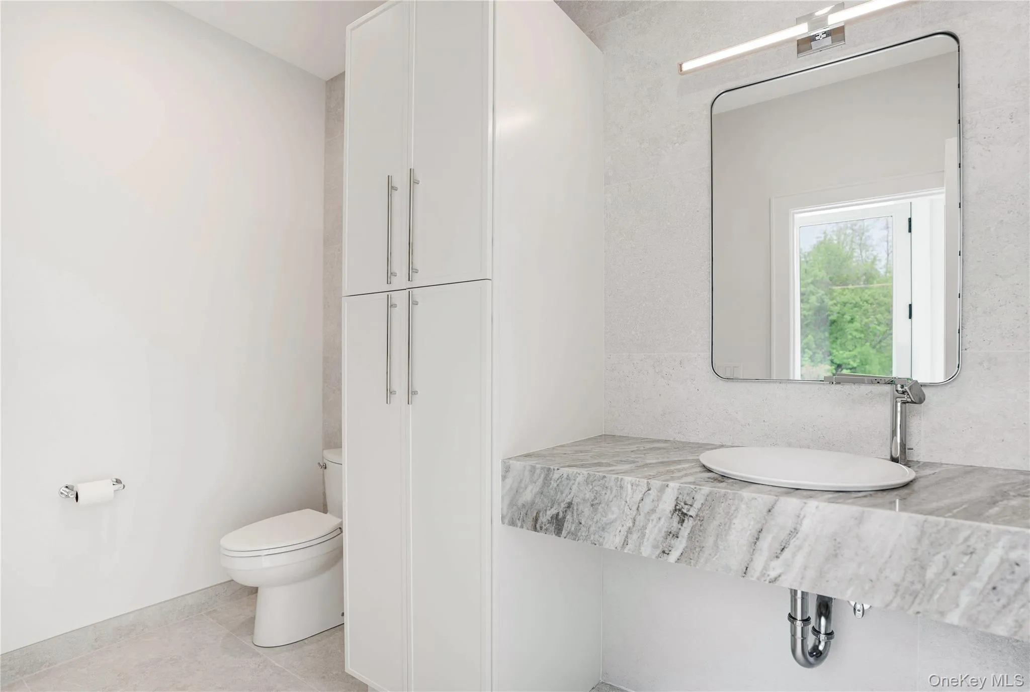 Bathroom with toilet, a sink, tile patterned floors, and baseboards Bathroom with toilet, a sink, tile patterned floors, and baseboards