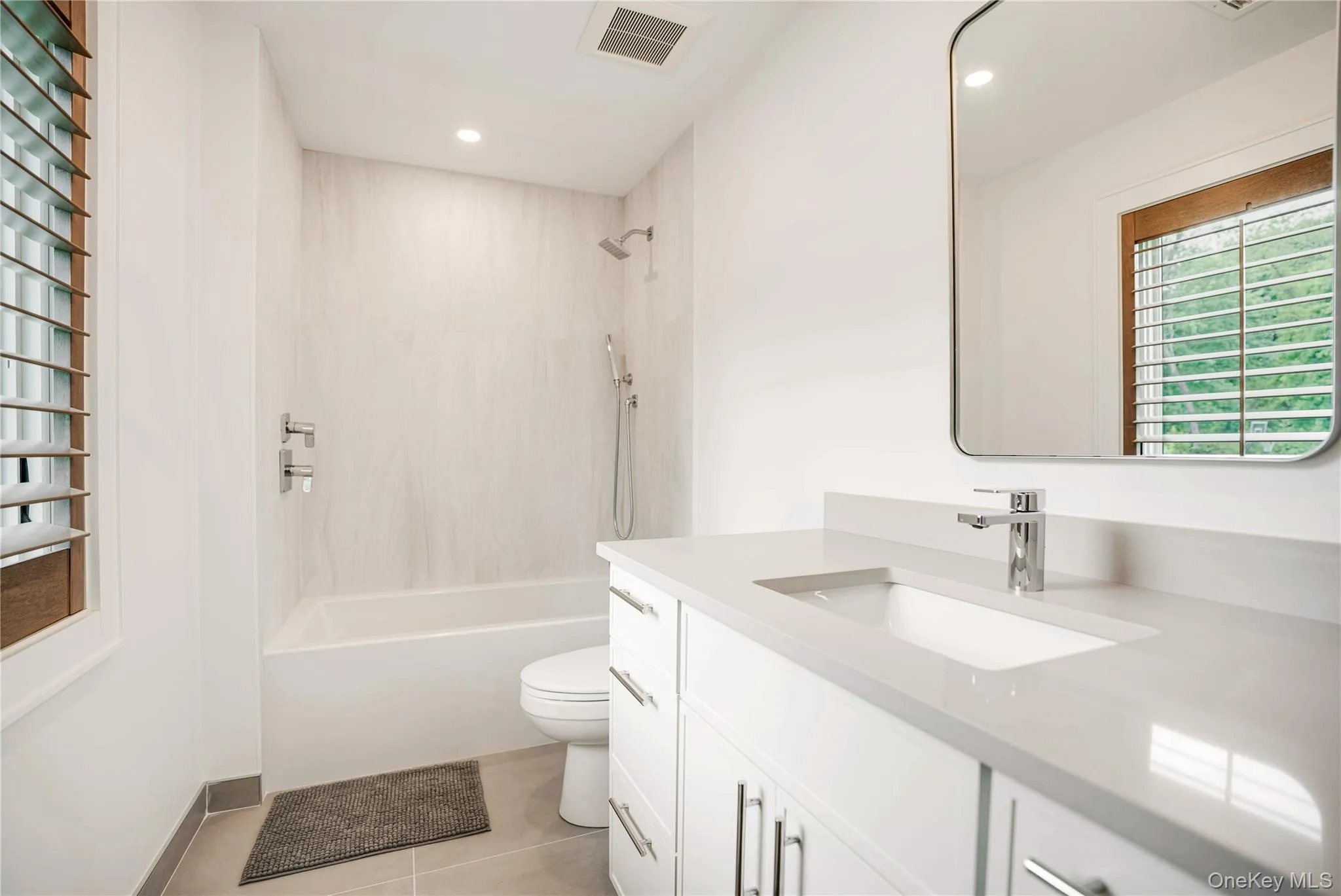Bathroom featuring toilet, tile patterned floors, vanity, washtub / shower combination, and recessed lighting Bathroom featuring toilet, tile patterned floors, vanity, washtub / shower combination, and recessed lighting