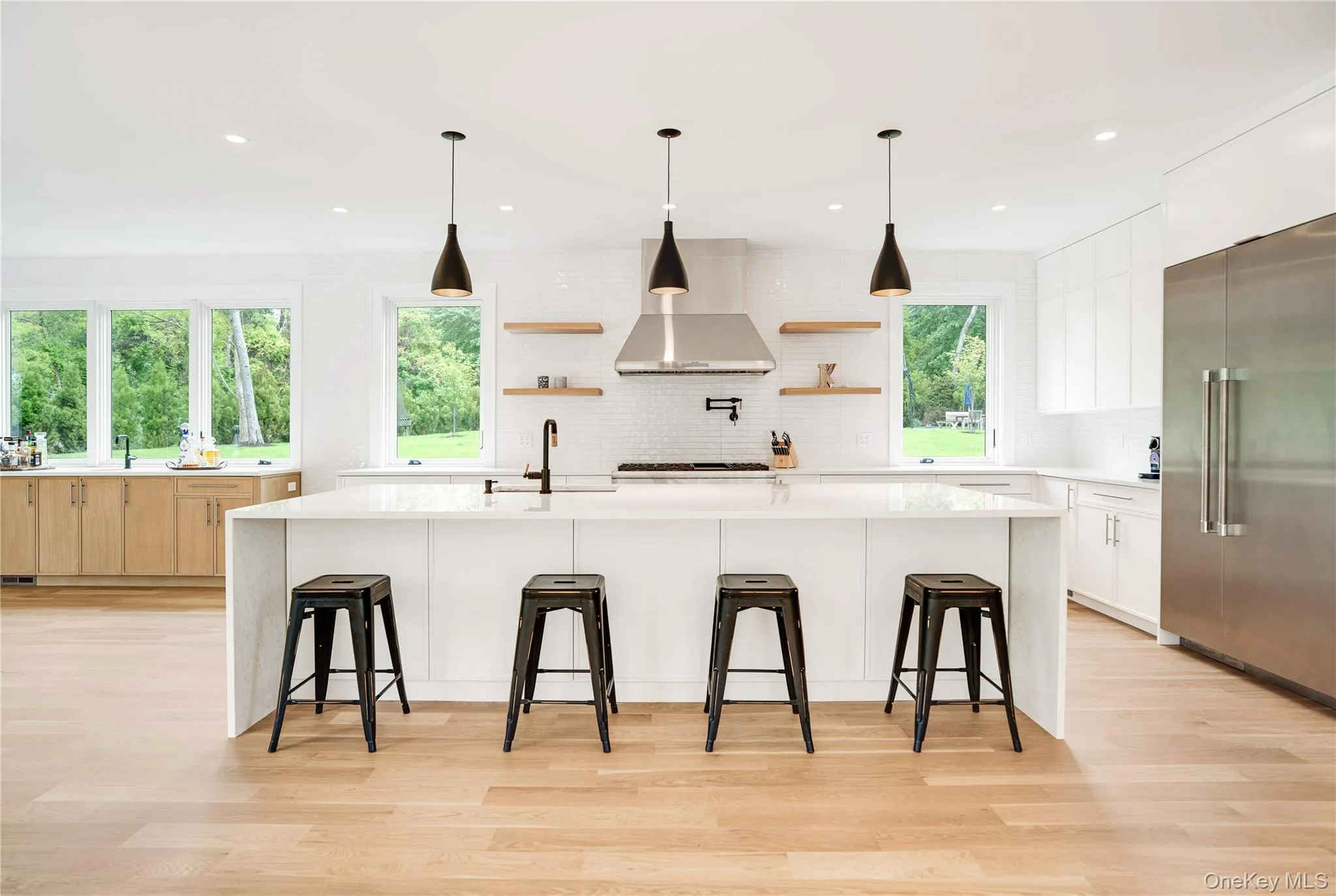 Kitchen with high end refrigerator, wall chimney range hood, open shelves, a sink, and backsplash Kitchen with high end refrigerator, wall chimney range hood, open shelves, a sink, and backsplash