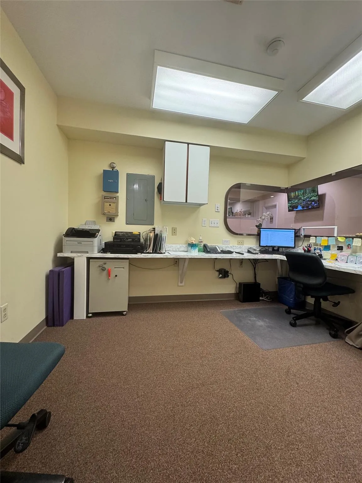 Office space featuring carpet flooring, electric panel, and built in desk Office space featuring carpet flooring, electric panel, and built in desk