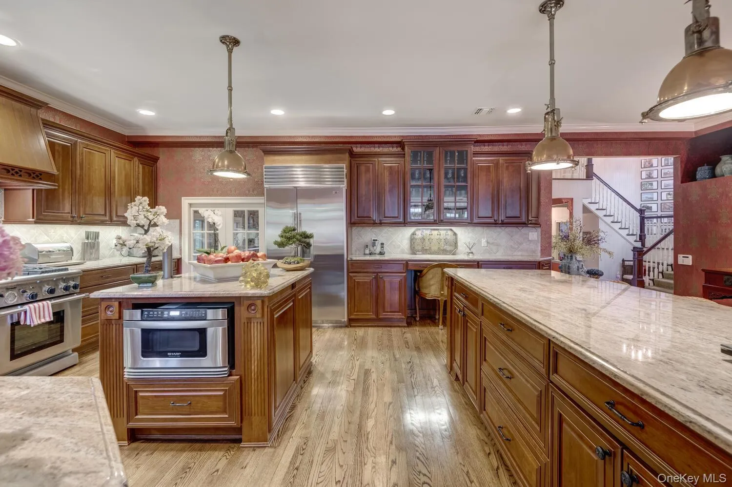 Kitchen featuring premium appliances, tasteful backsplash, light wood-style flooring, light stone counters, and glass insert cabinets Kitchen featuring premium appliances, tasteful backsplash, light wood-style flooring, light stone counters, and glass insert cabinets