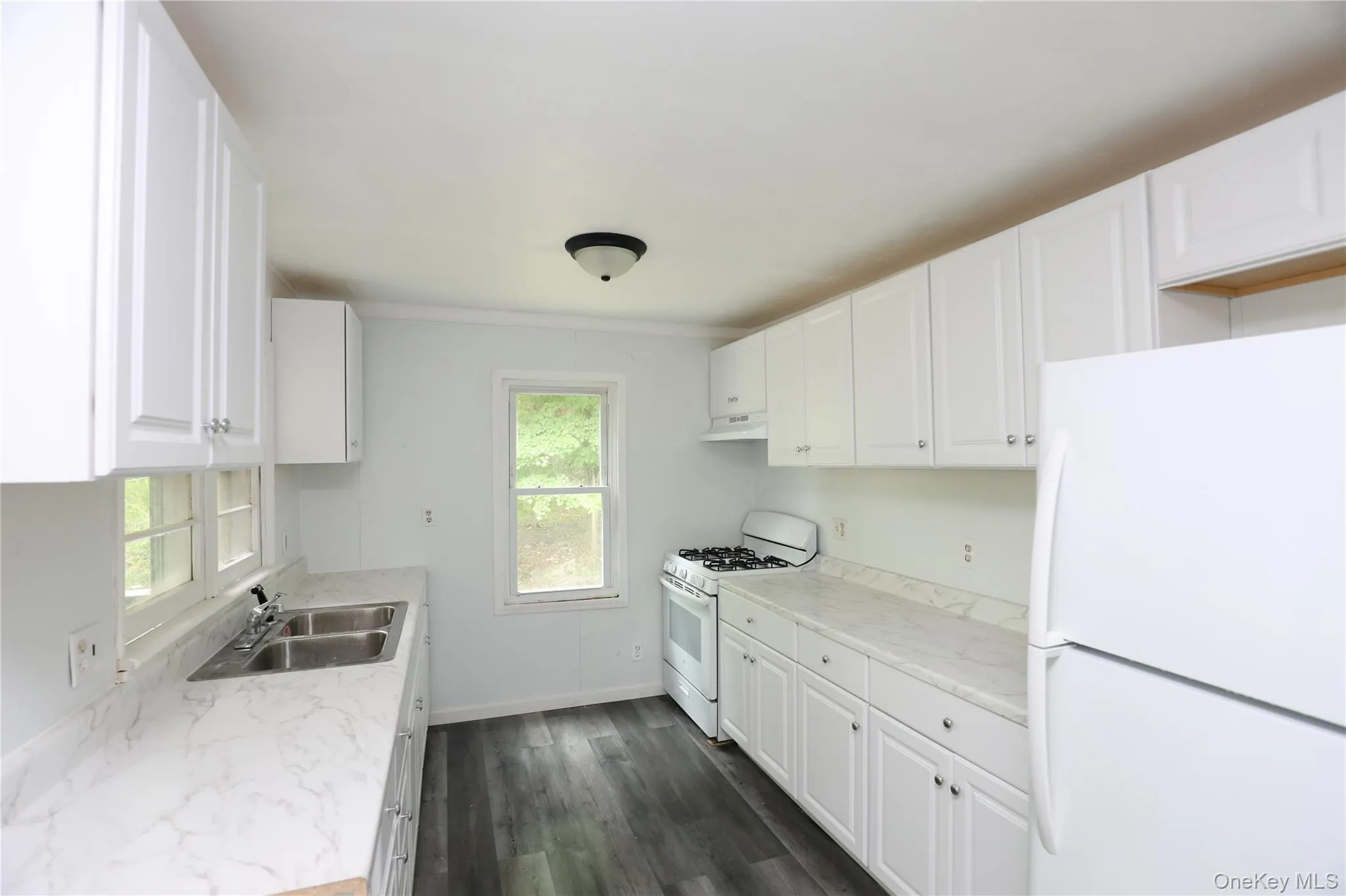 Kitchen with white appliances, a sink, healthy amount of natural light, and white cabinetry Kitchen with white appliances, a sink, healthy amount of natural light, and white cabinetry
