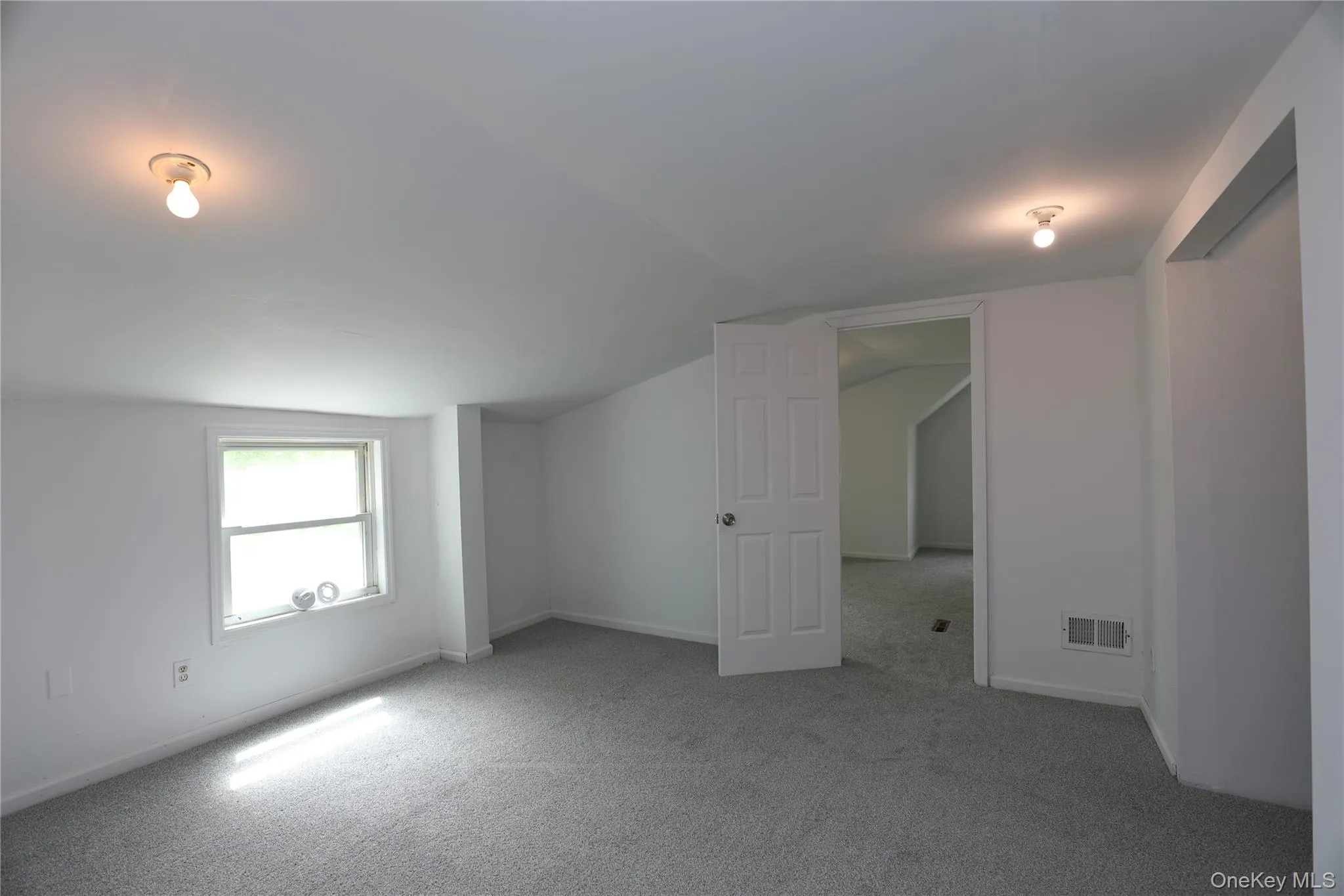 Carpeted empty room featuring lofted ceiling and baseboards Carpeted empty room featuring lofted ceiling and baseboards