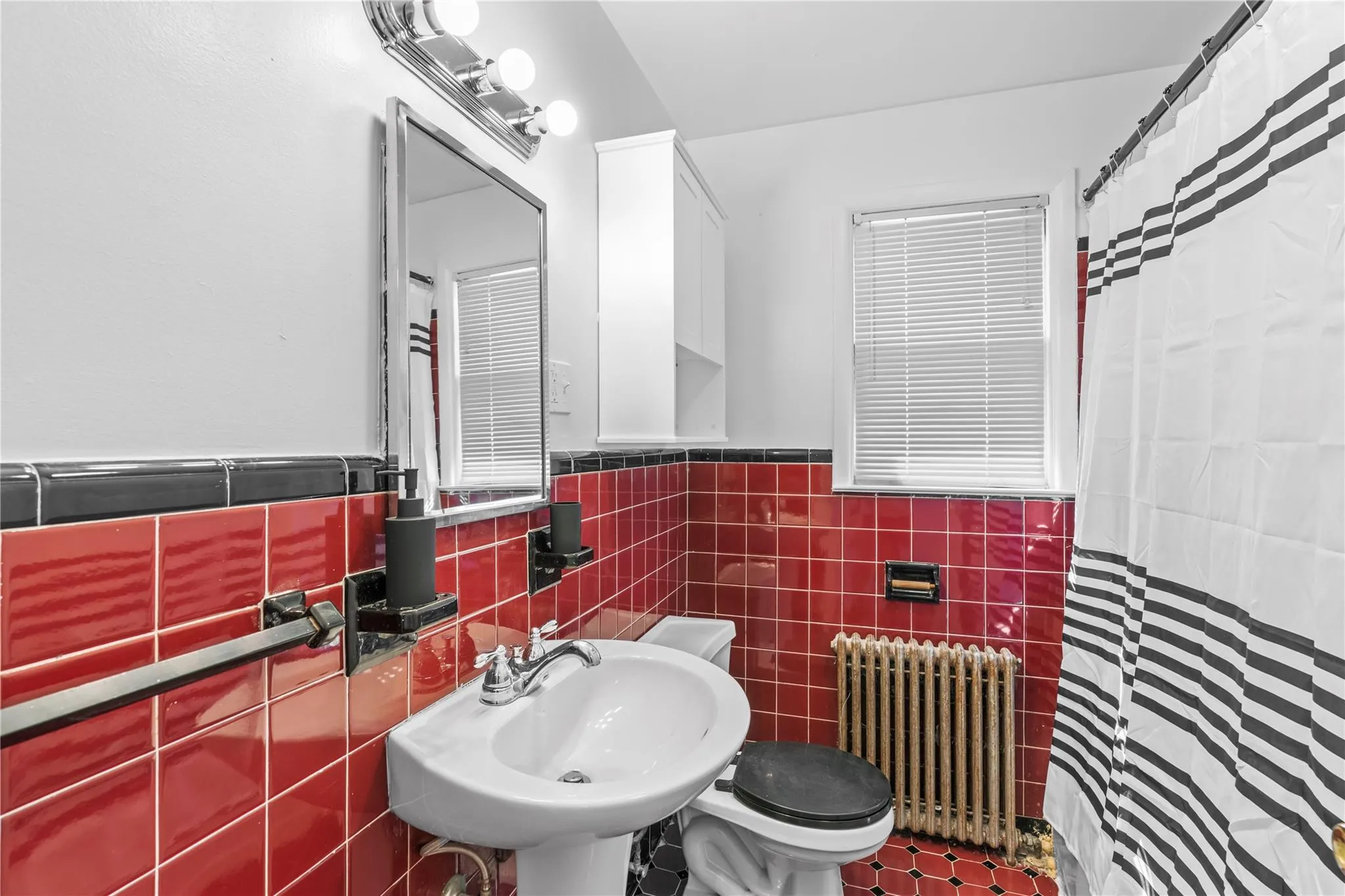 Full bath with radiator heating unit, a sink, toilet, tile walls, and a shower with curtain Full bath with radiator heating unit, a sink, toilet, tile walls, and a shower with curtain