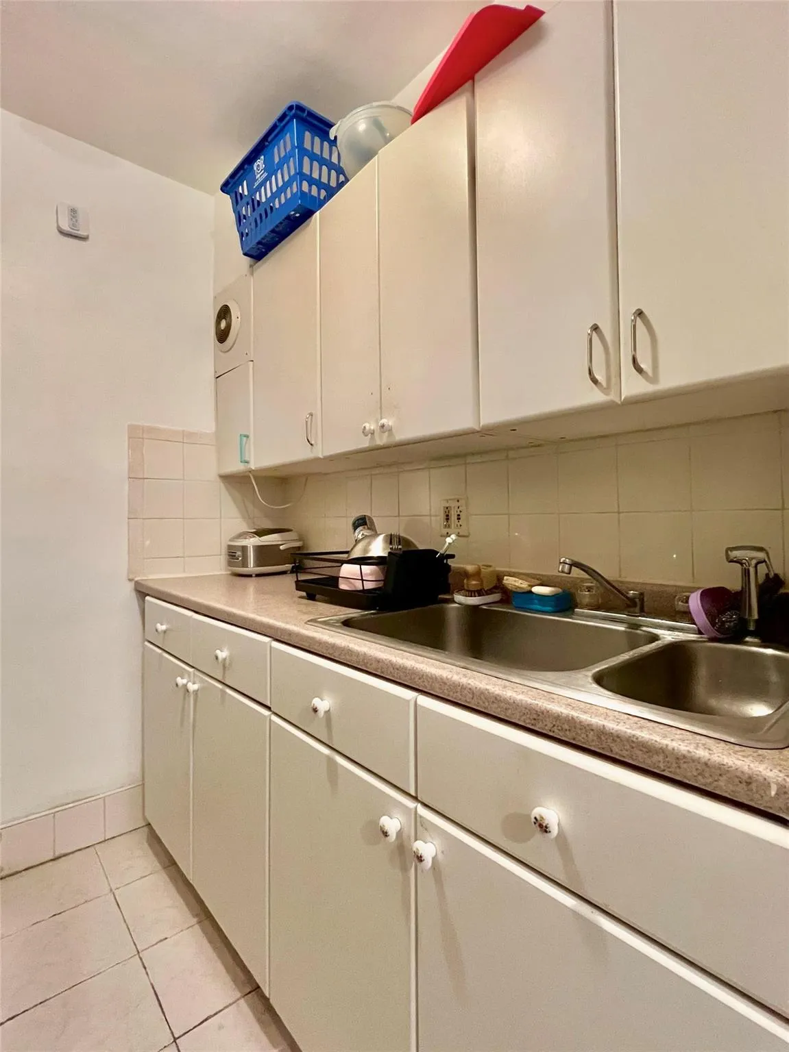 Kitchen featuring a sink, backsplash, white cabinetry, and light tile patterned flooring Kitchen featuring a sink, backsplash, white cabinetry, and light tile patterned flooring