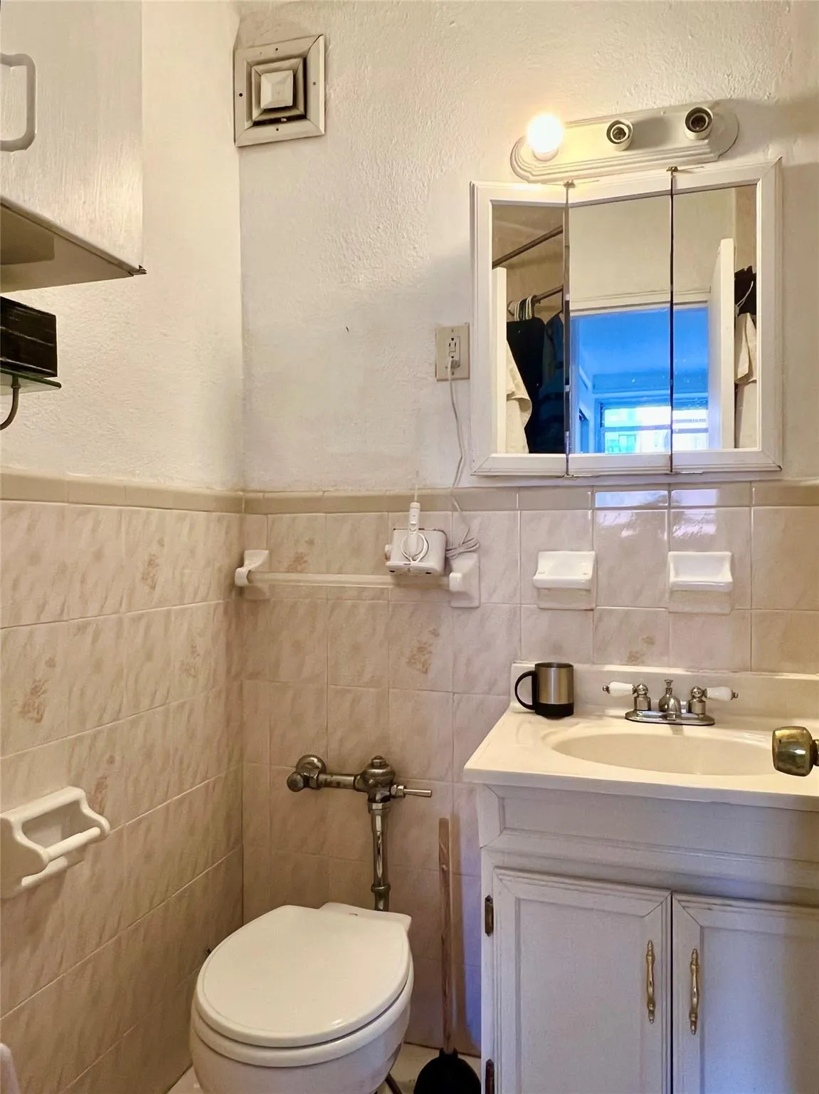 Bathroom featuring tile walls, vanity, toilet, and wainscoting Bathroom featuring tile walls, vanity, toilet, and wainscoting