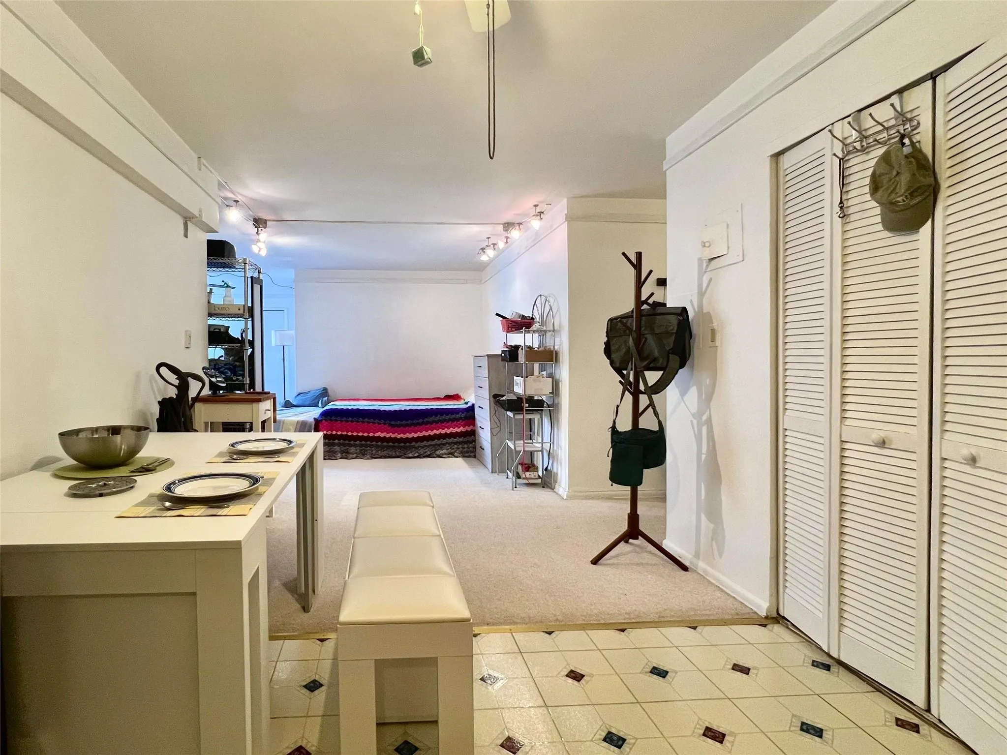 Hallway featuring light carpet, track lighting, and baseboards Hallway featuring light carpet, track lighting, and baseboards