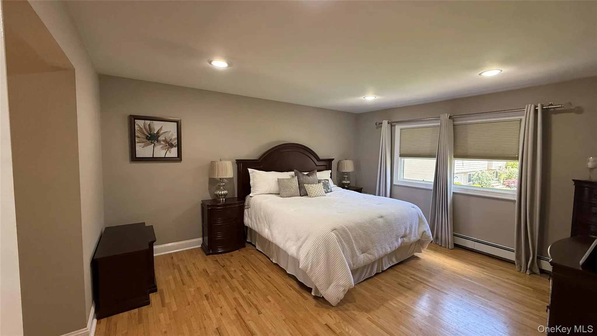 Bedroom featuring a baseboard heating unit, light wood-type flooring, baseboards, and recessed lighting Bedroom featuring a baseboard heating unit, light wood-type flooring, baseboards, and recessed lighting