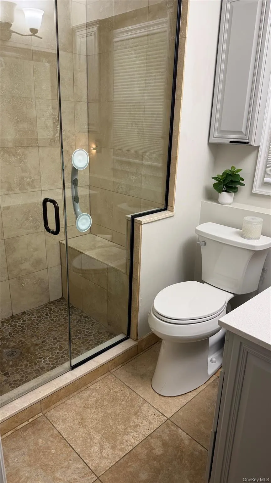 Bathroom featuring vanity, toilet, a stall shower, and tile patterned floors Bathroom featuring vanity, toilet, a stall shower, and tile patterned floors