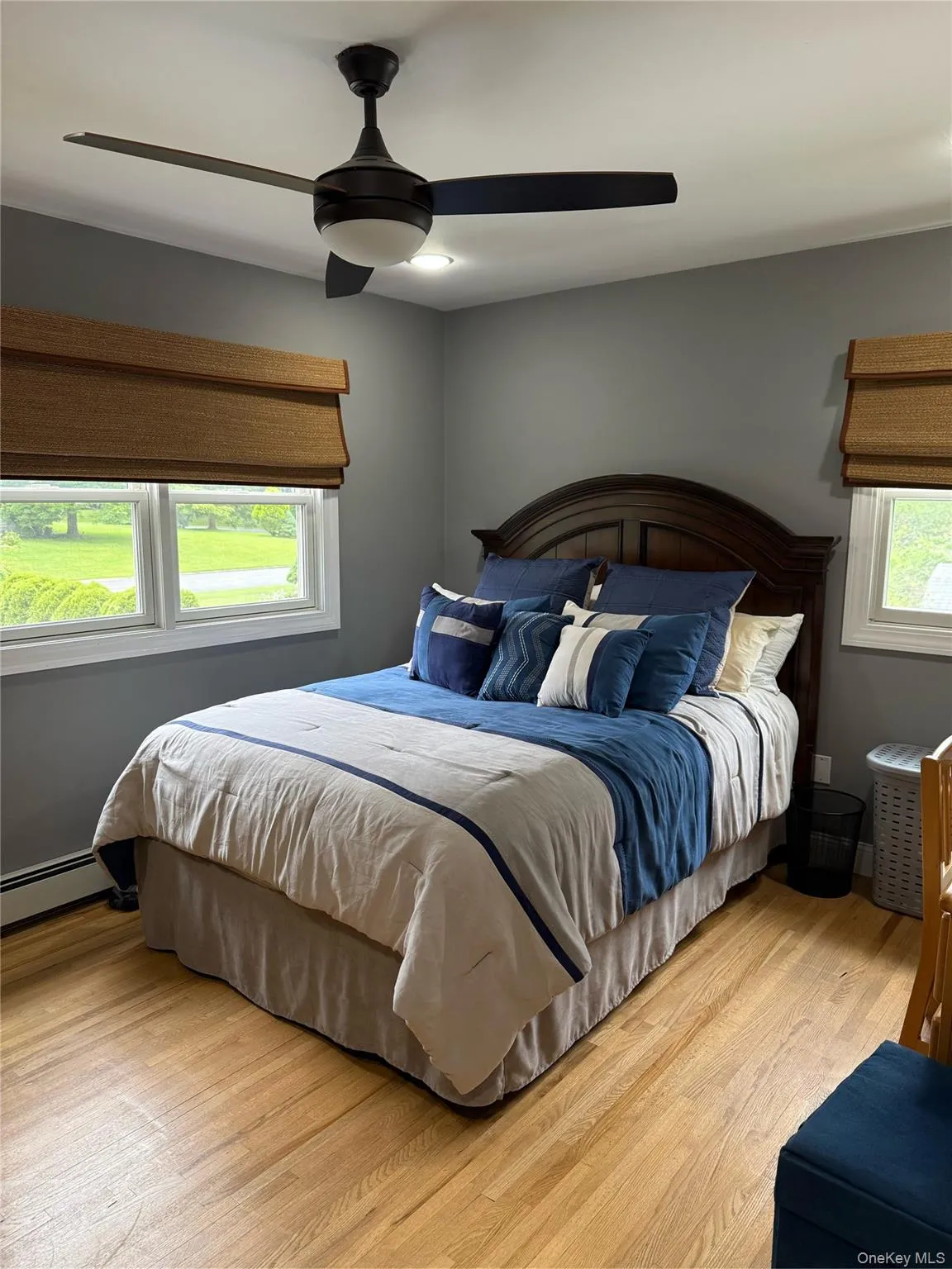 Bedroom featuring wood finished floors, a ceiling fan, and baseboard heating Bedroom featuring wood finished floors, a ceiling fan, and baseboard heating