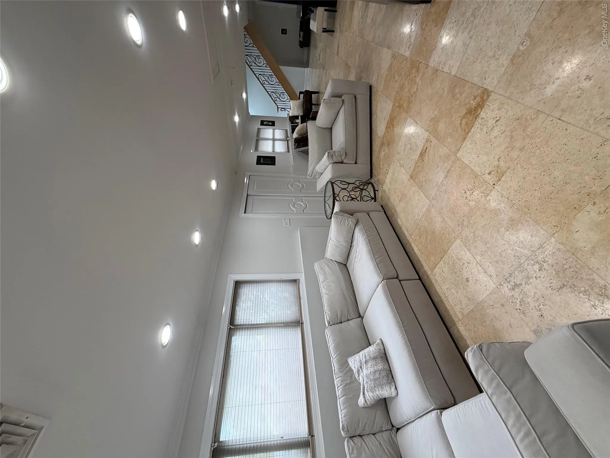 Living room with recessed lighting, ornamental molding, stairs, stone tile flooring, and baseboards Living room with recessed lighting, ornamental molding, stairs, stone tile flooring, and baseboards