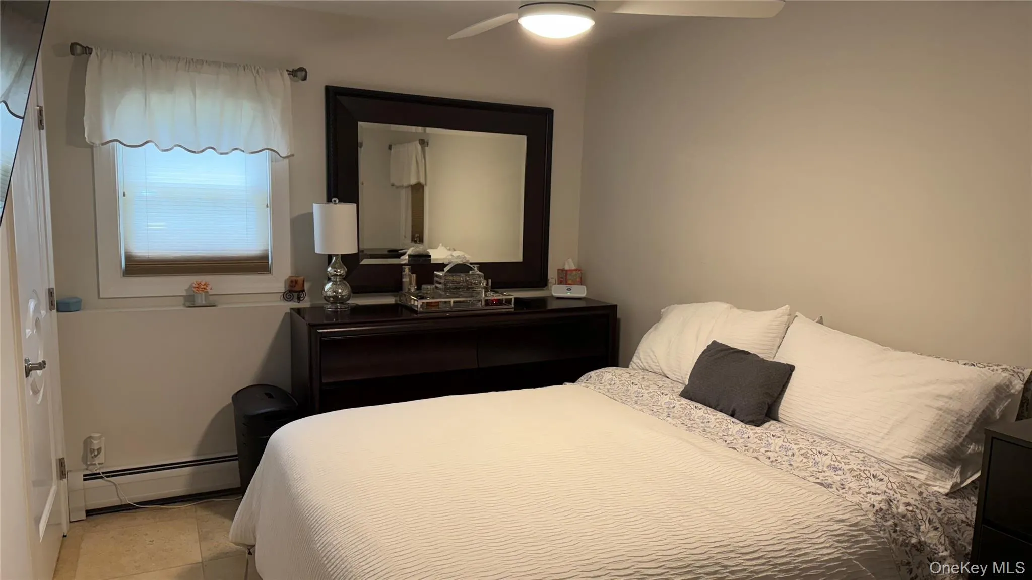 Bedroom with a baseboard radiator, a ceiling fan, and light tile patterned floors Bedroom with a baseboard radiator, a ceiling fan, and light tile patterned floors