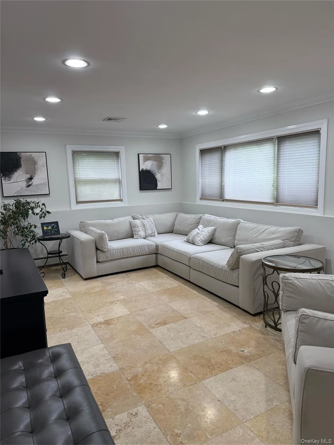 Living room with crown molding, recessed lighting, and stone tile floors Living room with crown molding, recessed lighting, and stone tile floors