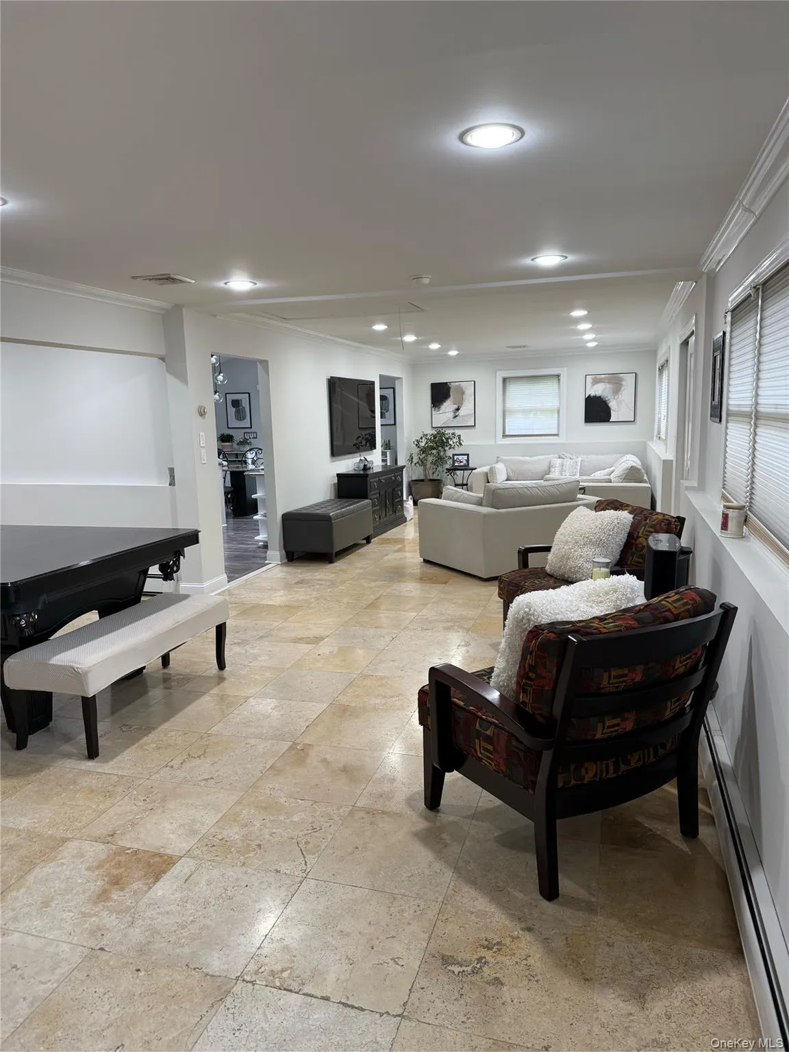 Living room featuring ornamental molding, recessed lighting, baseboard heating, stone tile floors, and baseboards Living room featuring ornamental molding, recessed lighting, baseboard heating, stone tile floors, and baseboards