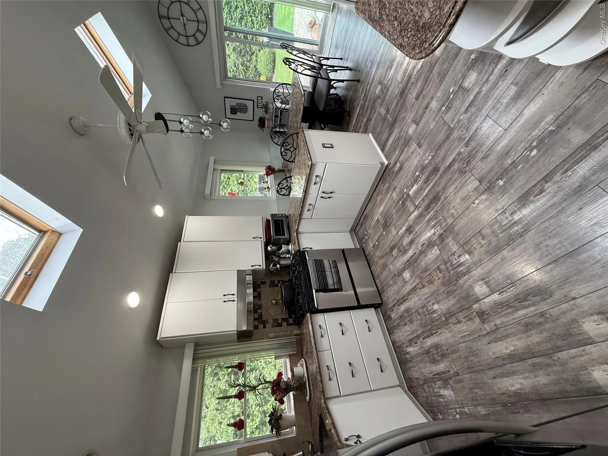 Kitchen featuring a skylight, range, a peninsula, white cabinetry, and vaulted ceiling Kitchen featuring a skylight, range, a peninsula, white cabinetry, and vaulted ceiling