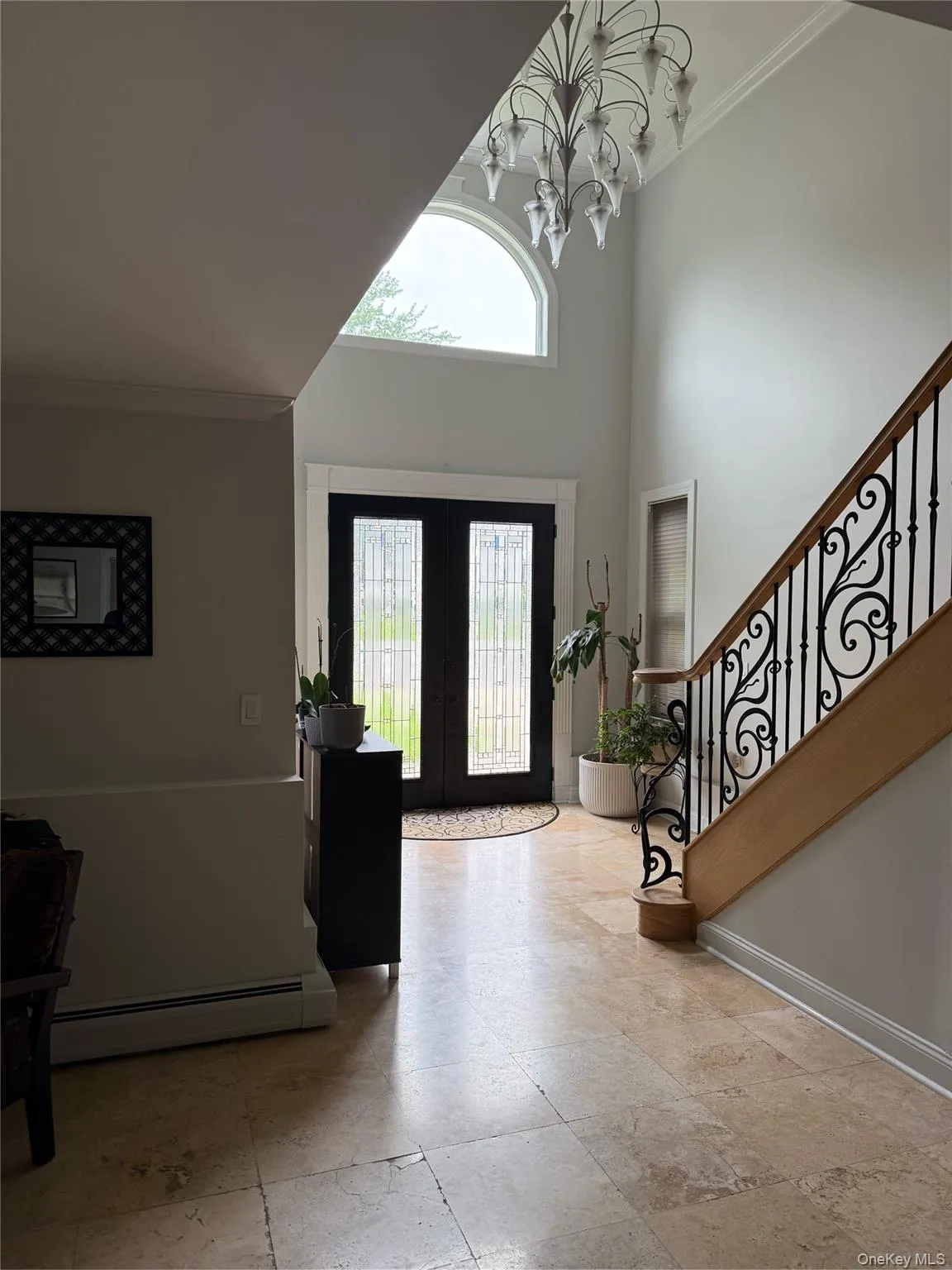 Entryway featuring a baseboard heating unit, crown molding, french doors, stairway, and a chandelier Entryway featuring a baseboard heating unit, crown molding, french doors, stairway, and a chandelier