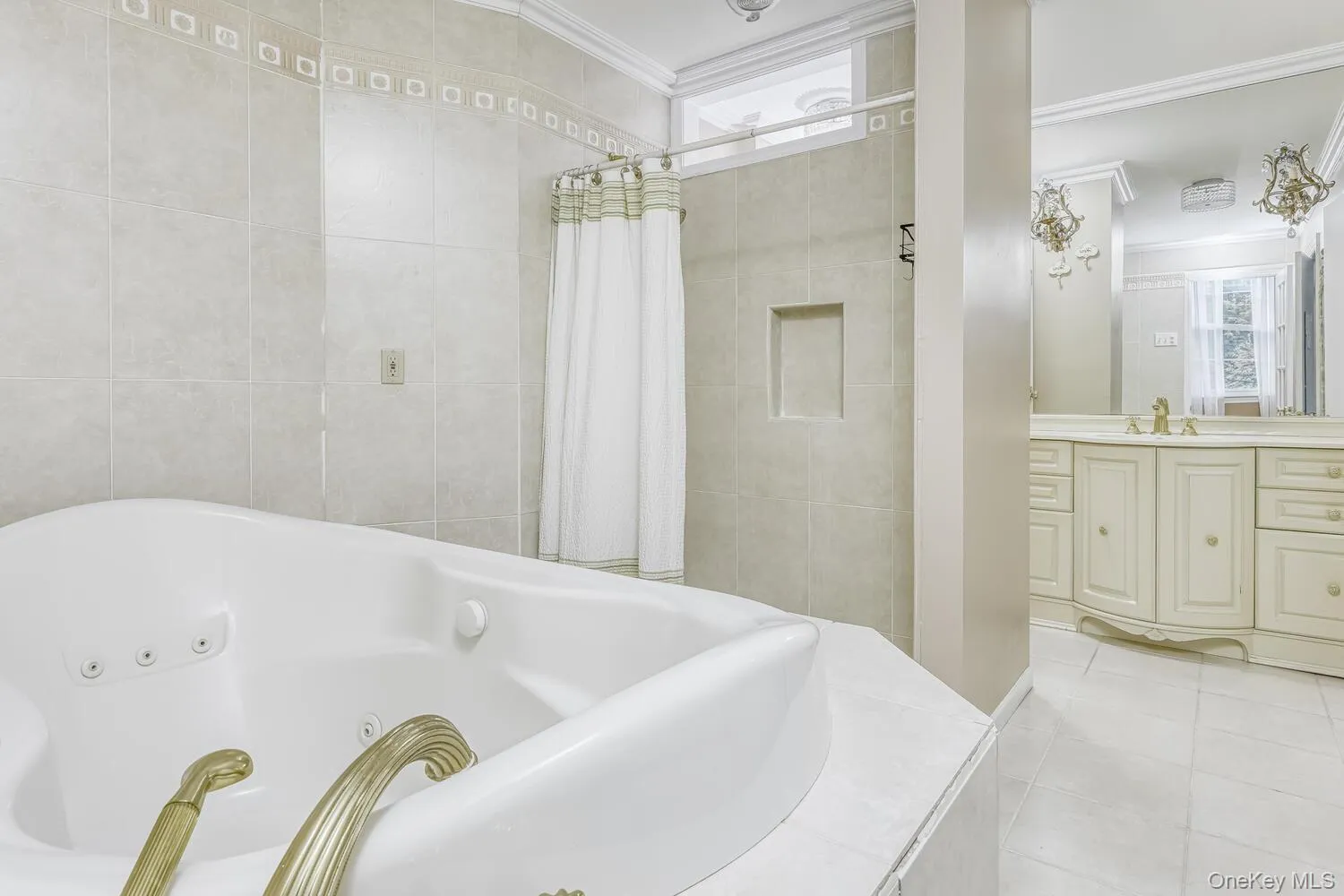 Full bathroom featuring a tub with jets, crown molding, tile patterned floors, vanity, and tile walls Full bathroom featuring a tub with jets, crown molding, tile patterned floors, vanity, and tile walls