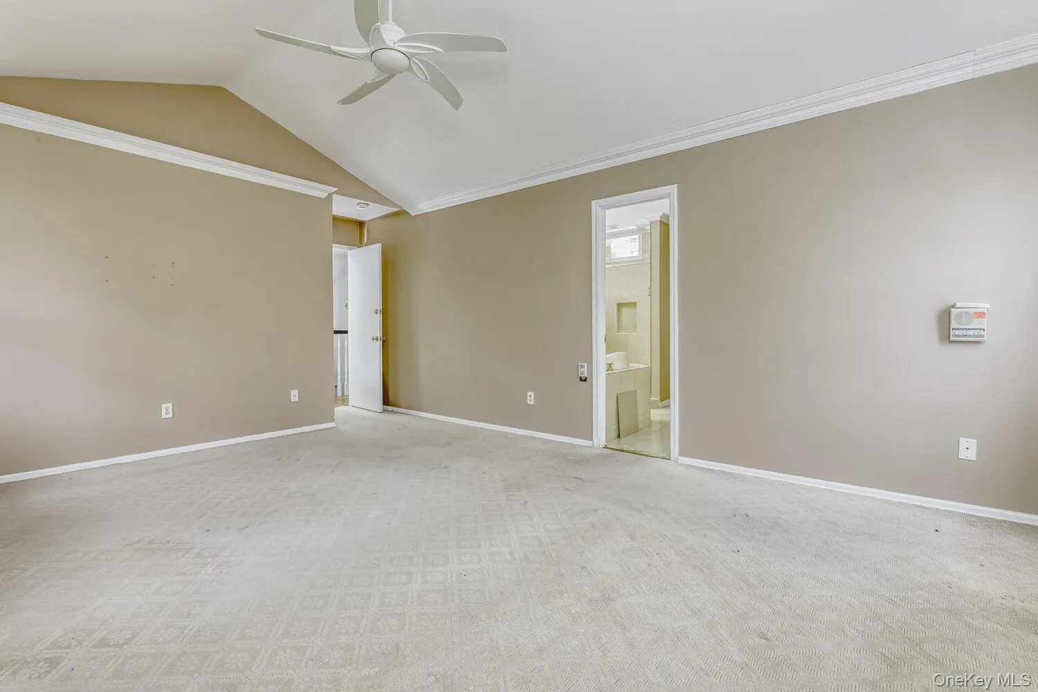 Unfurnished room with a ceiling fan, lofted ceiling, baseboards, crown molding, and light carpet Unfurnished room with a ceiling fan, lofted ceiling, baseboards, crown molding, and light carpet