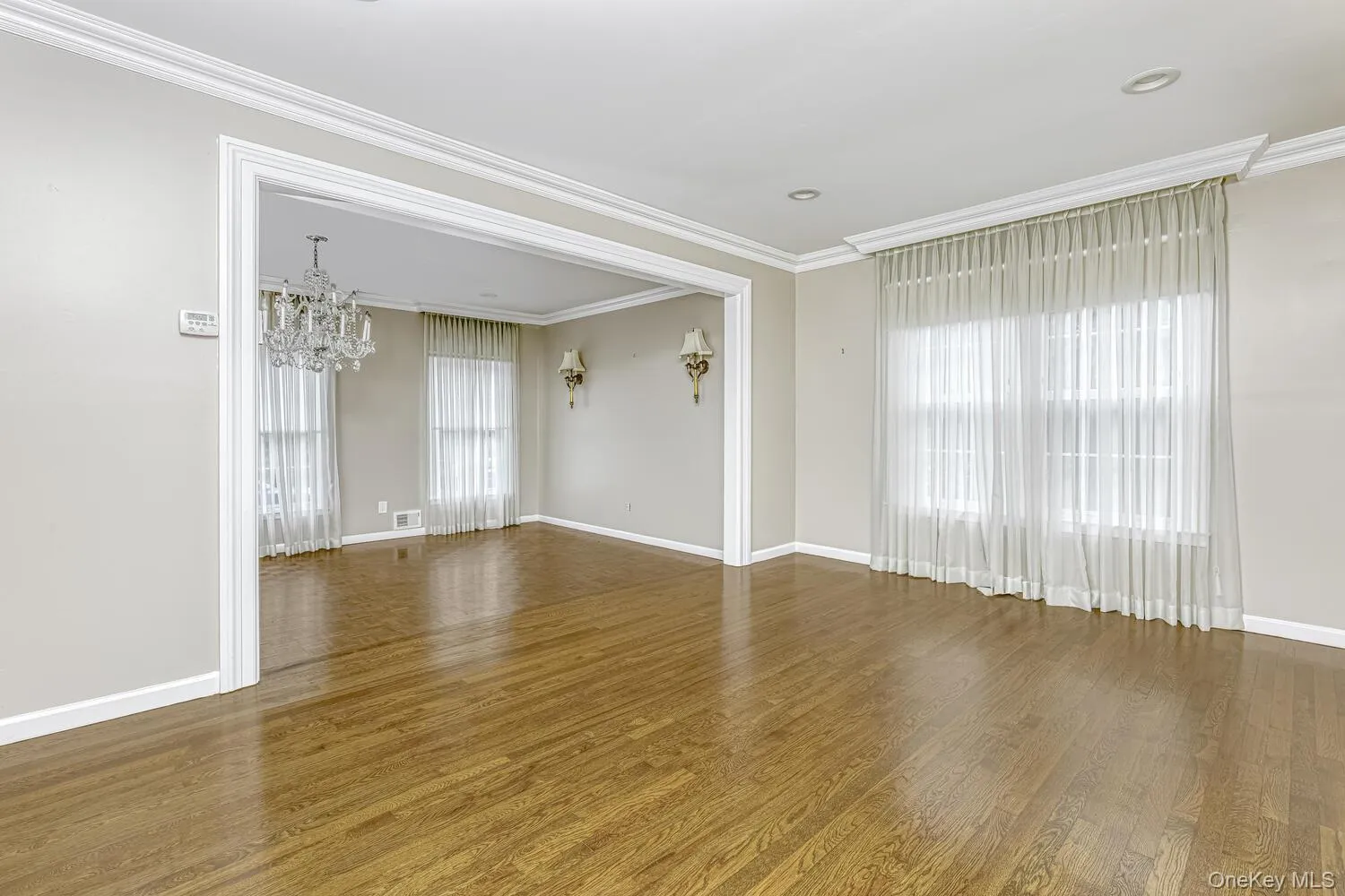 Unfurnished room with a chandelier, plenty of natural light, wood finished floors, baseboards, and ornamental molding Unfurnished room with a chandelier, plenty of natural light, wood finished floors, baseboards, and ornamental molding